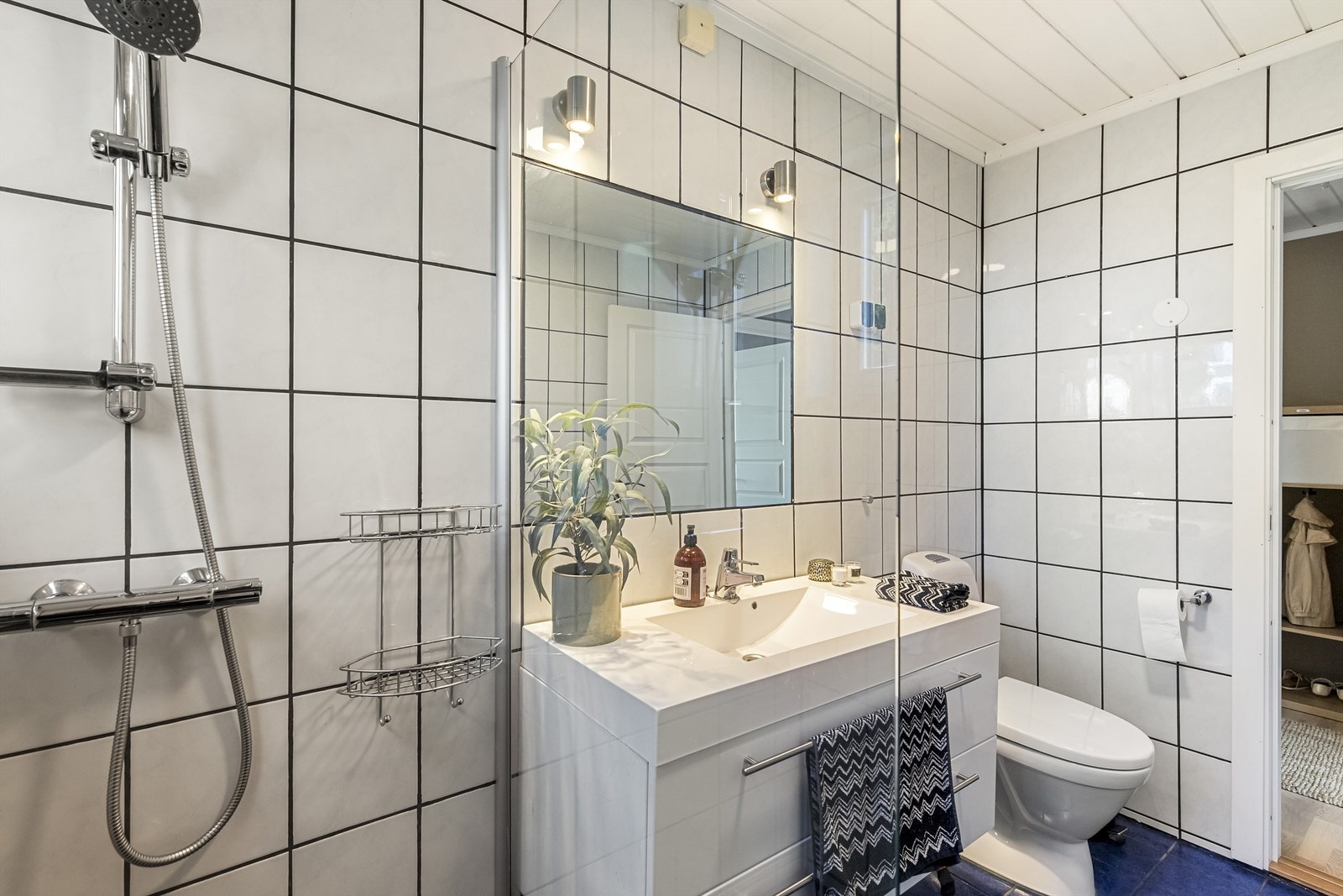 Badet i første etasje har flislagte overflater, veggmontert dusj og toalett. Galleribilde