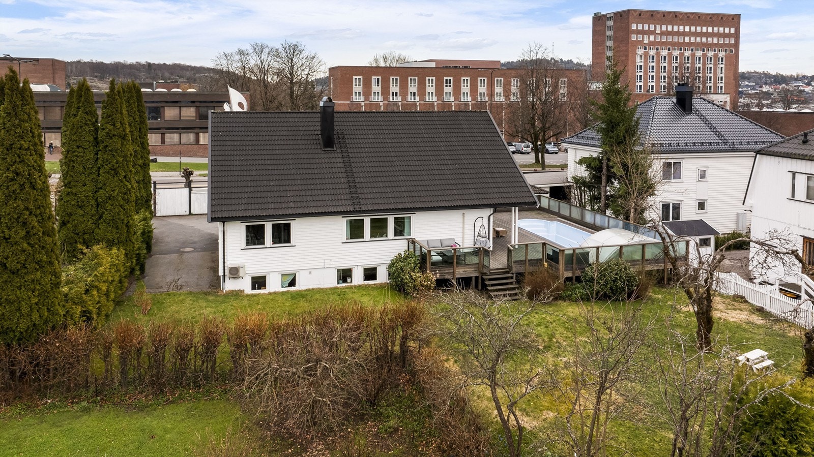 Eiendommen sett fra hagesiden, med terrassen og bassenget sentralt plassert. Galleribilde