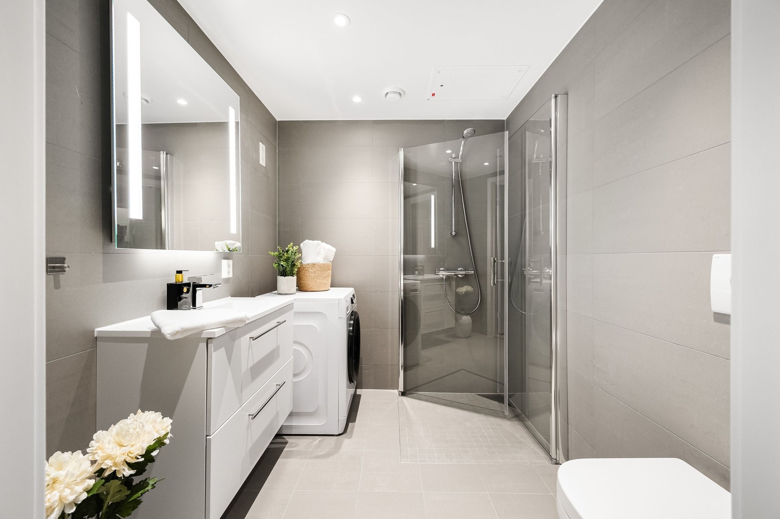 Lekkert baderom med store, lyse fliser på vegger og gulv, som gir et stilrent uttrykk Galleribilde