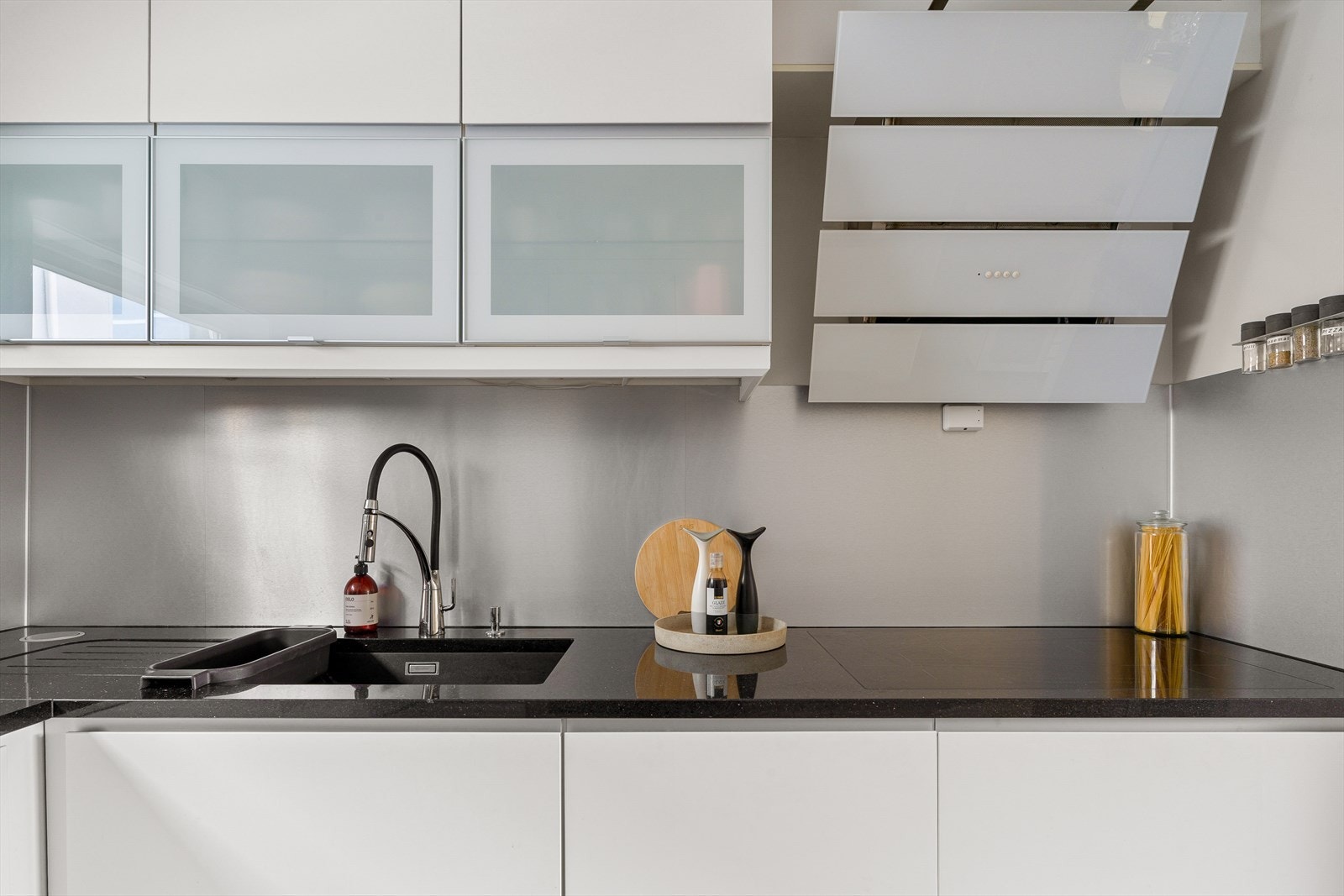 Kjøkken med mørk benkeplate, nedfelt vask og moderne ventilator. Galleribilde