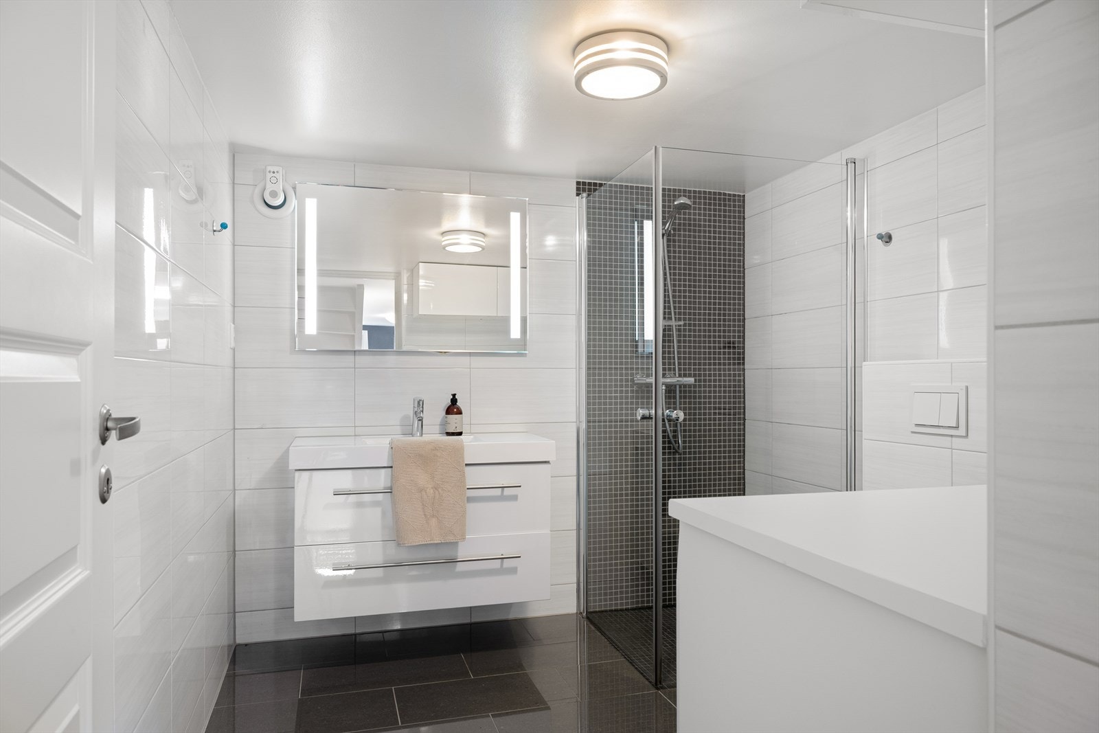 Badet i kjeller er helfliset og innredet med vask i seksjon, vegghengt toalett og dusjhjørne. Det er også opplegg for vaskemaskin og tørketrommel. Galleribilde