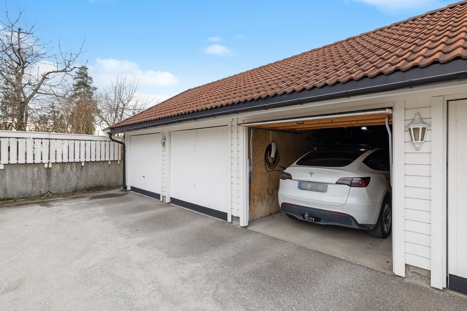Boligen har garasjeplass i felles rekke med montert Tesla-lader. Galleribilde