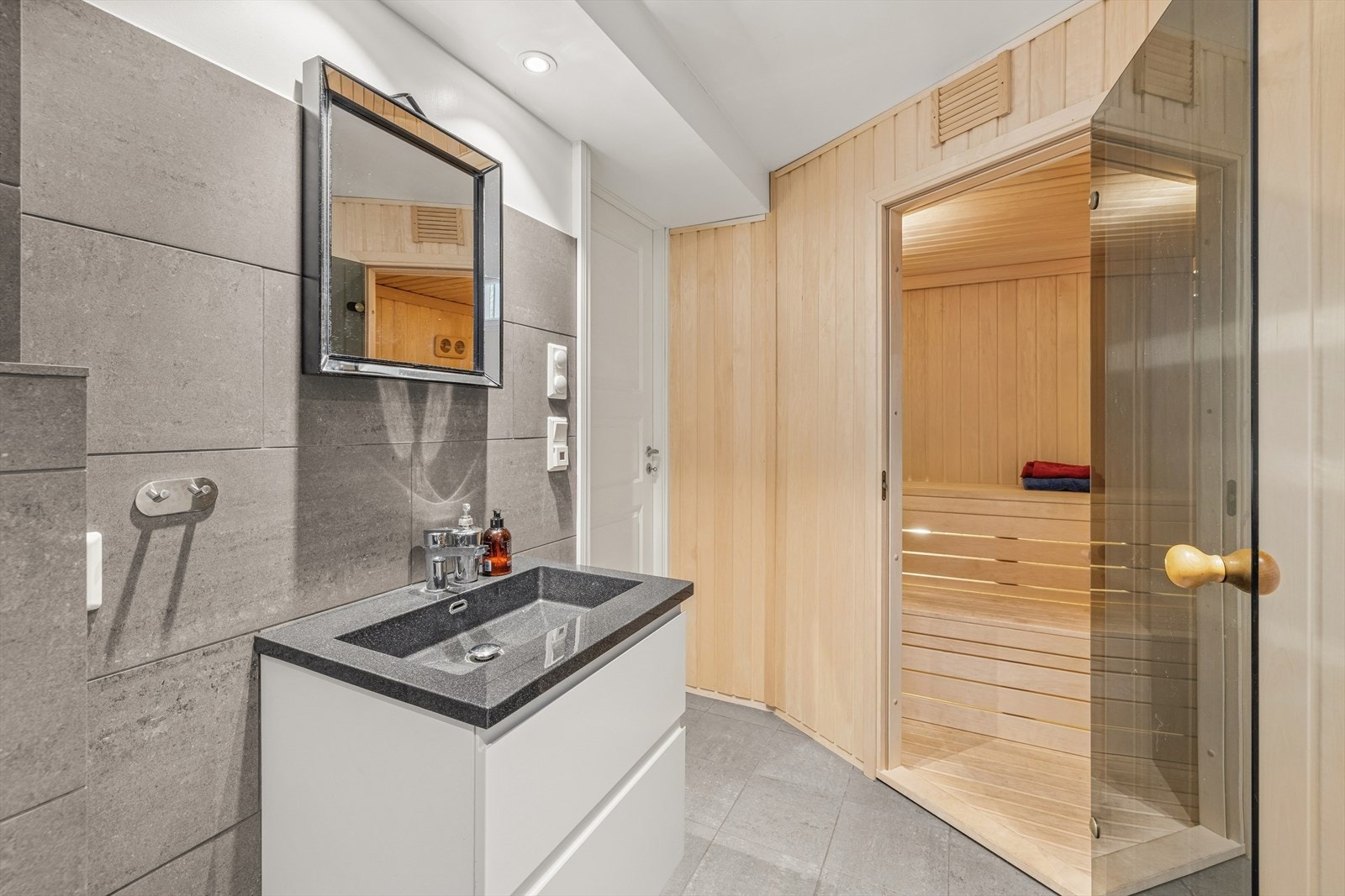 Badet har innredning med servant med underskap, speil med tilhørende belysning, vegghengt wc, opplegg for vaskemaskin og utslagsvask. Fra badet er det direkte adkomst til badstuen. Galleribilde