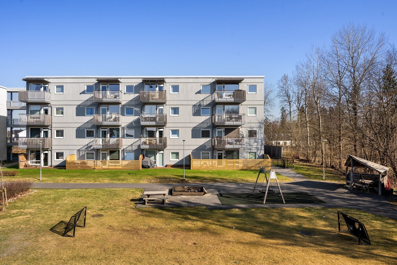 Tomten opparbeidet med asfalterte internveier, sittebenker, lekeapparater, plenarealer, prydbusker og diverse beplantning. Galleribilde