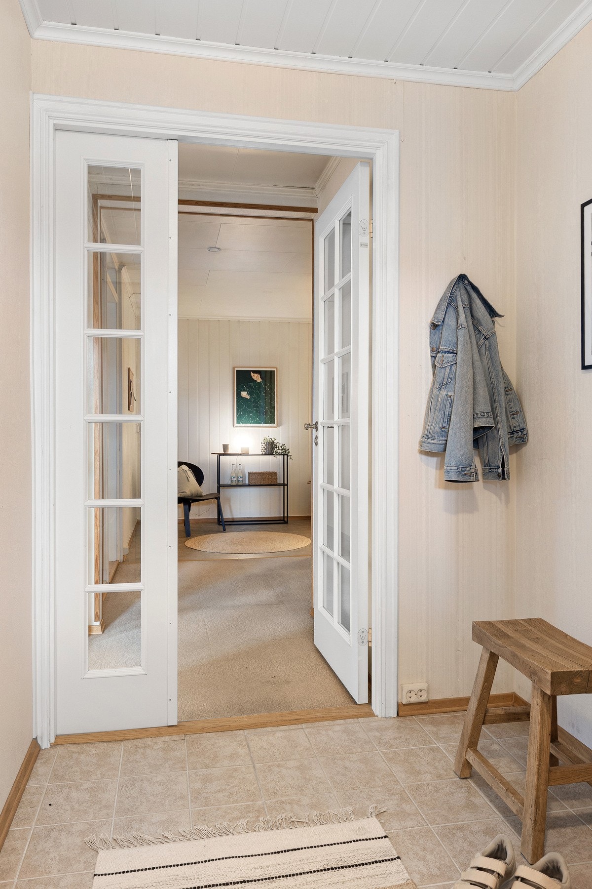 Døren med glassfelt slipper inn godt med dagslys og gir innsyn mot kjøkken. En åpen og hyggelig velkomstsone. Galleribilde