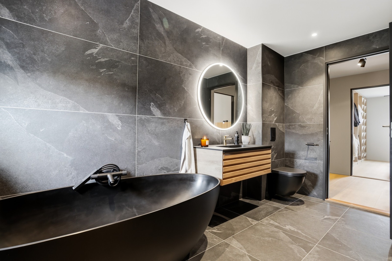 Store, mørke fliser i marmormønster gir et eksklusivt preg, og badet har downlights, varmekabler og vegghengt toalett. Galleribilde