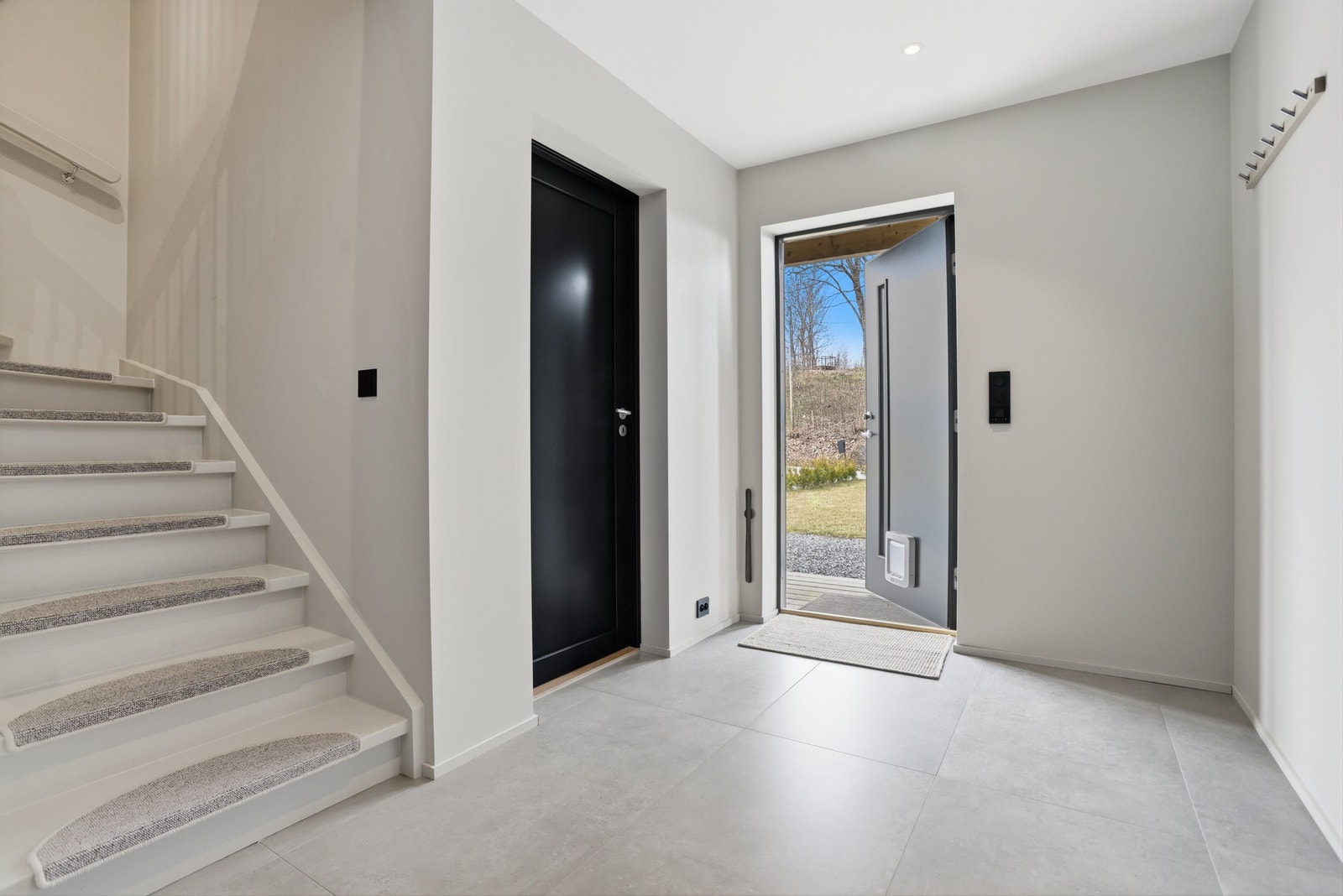 Velkommen inn i et innbydende familiehjem med god standard og høy komfort. Vel inne gir entreen et flott førsteinntrykk med downlights i taket, gråmalte veggflater og varme under store, lysegrå gulvfliser. Ekstra god takhøyde er gjennomgående, noe som bi Galleribilde