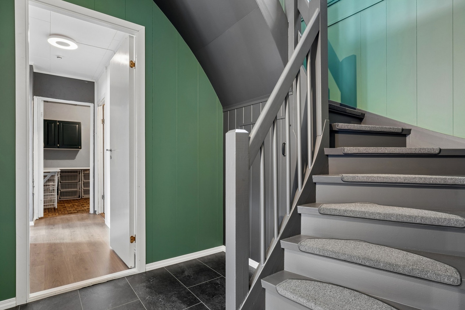 Den malte tretrappen med teppe i trinnene leder opp til hovedetasjen. Galleribilde