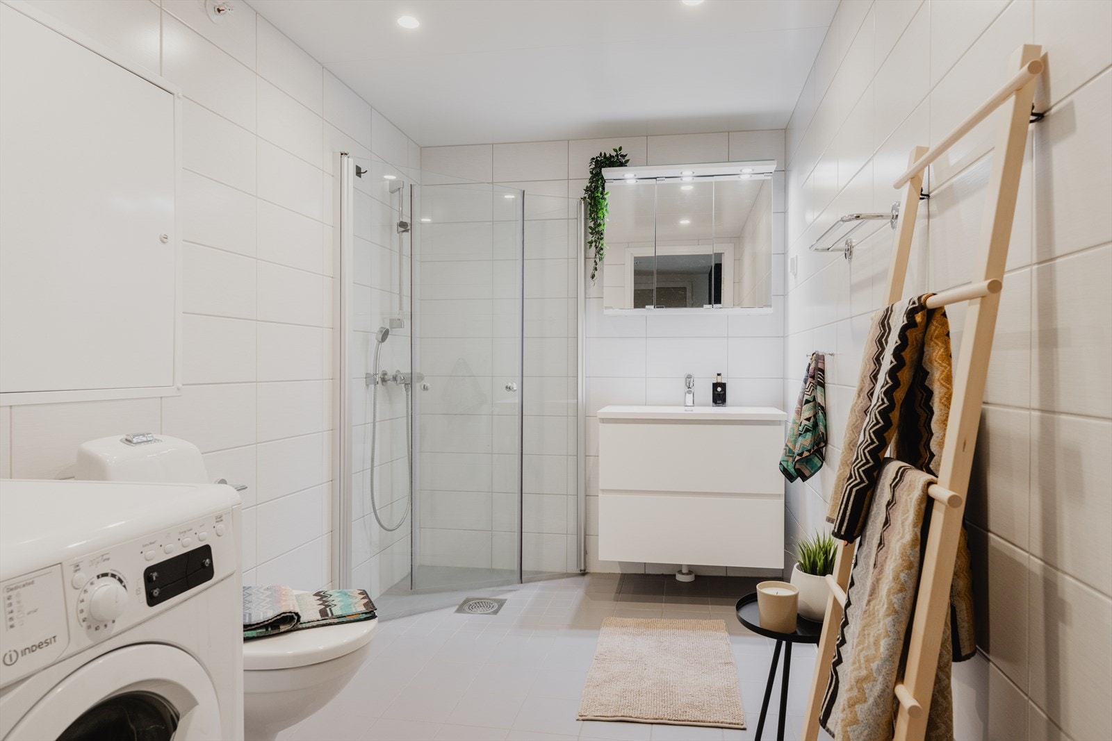 Badet er moderne og stilrent. Pent flislagte overfalter, vegghengt toalett, dusjhjørne og opplegg for vaskemaskin. Galleribilde