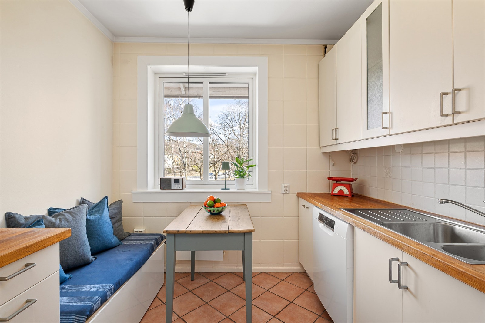 Separat kjøkken med plass til spisebord og sittebenk ved vinduet. Fra vinduet er det koselig utsyn over nabolaget og opp mot Grefsenåsen Galleribilde