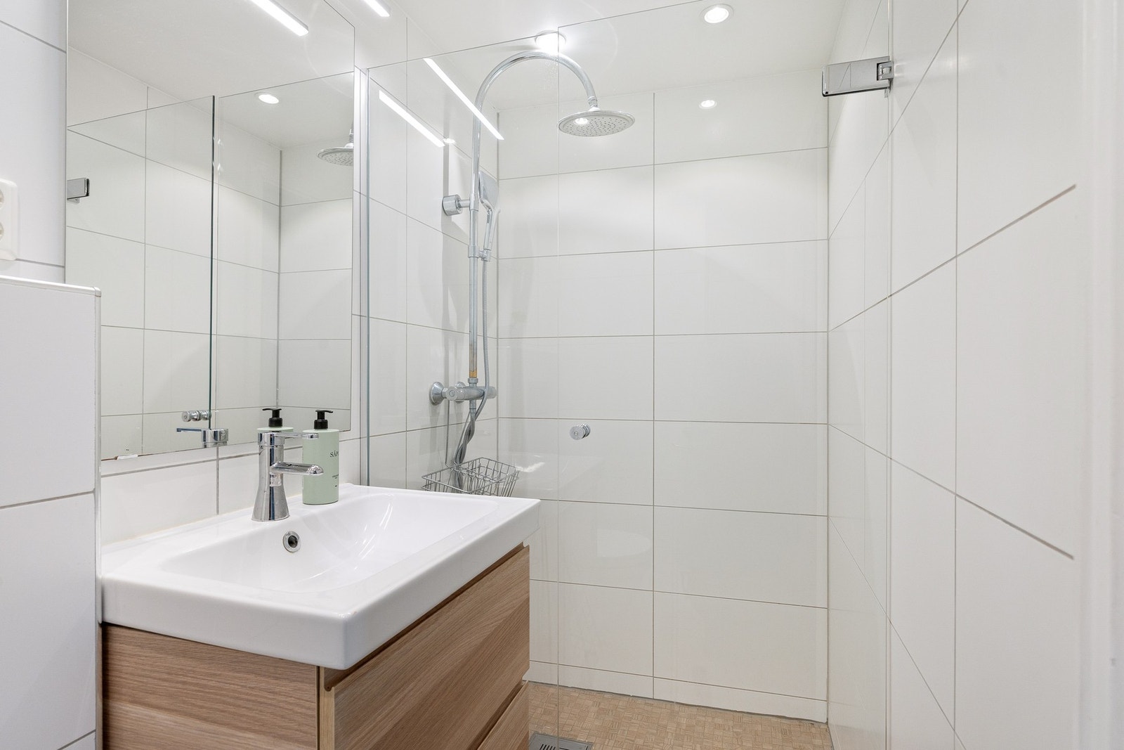 Badet består av vegghengt toalett, dusjsone med skillevegg i herdet glass og servantskap med nedfelt servant og speil. Galleribilde