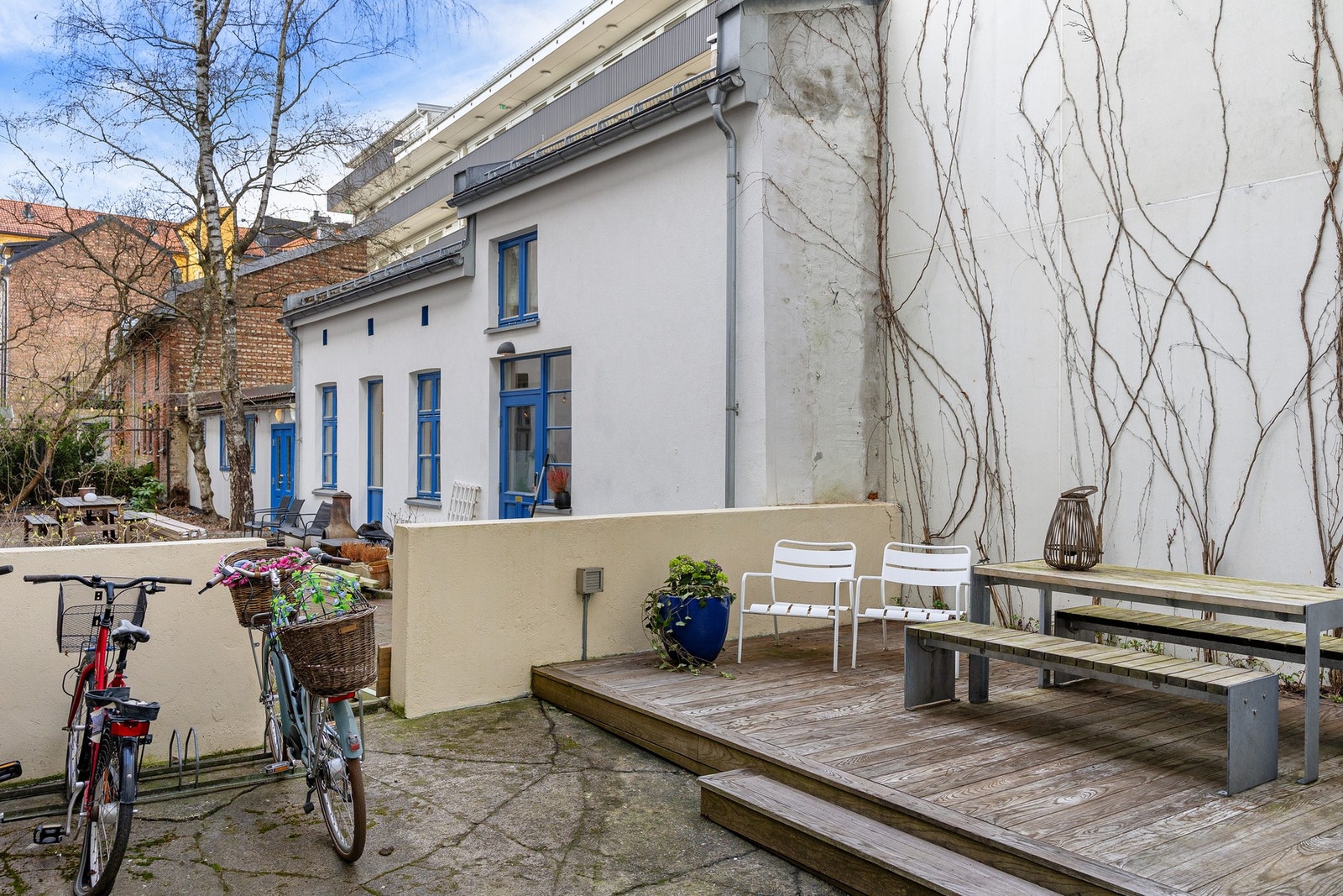 Pent opparbeidet og skjermet bakgård med hyggelige sittegrupper, beplantning og sykkelparkering. Galleribilde