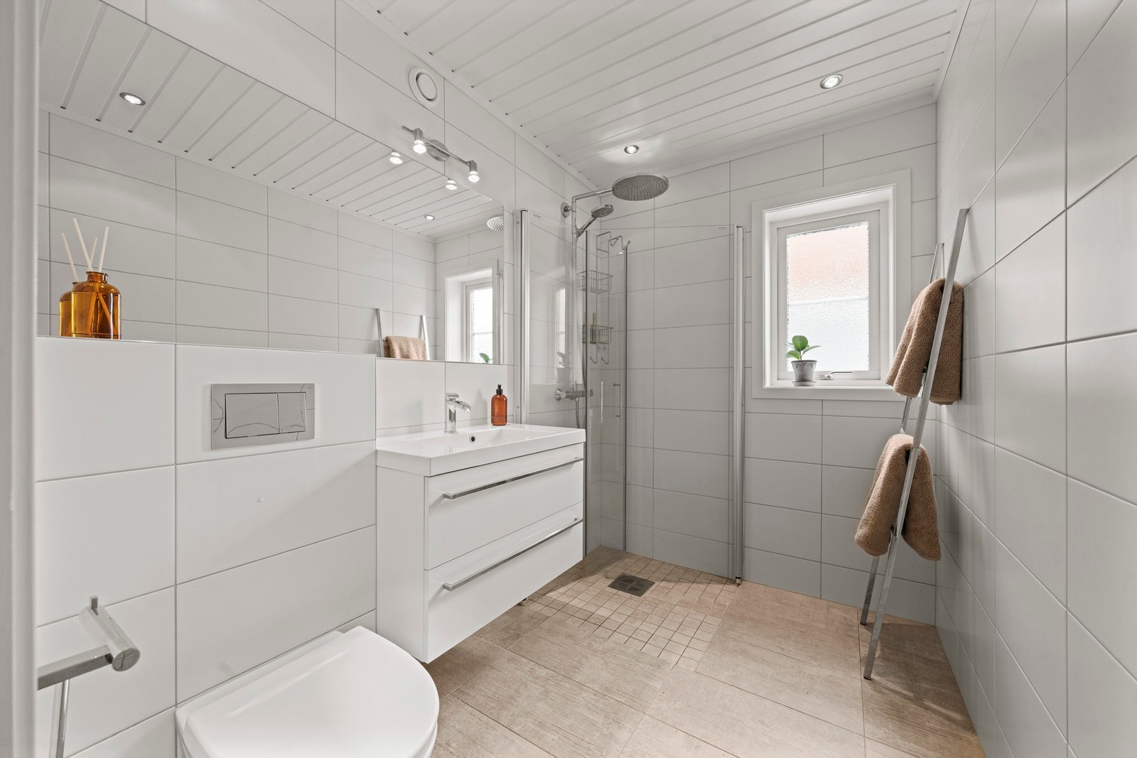 Badet har innredning med nedfelt servant, veggmontert toalett og dusjvegger/hjørne. Galleribilde