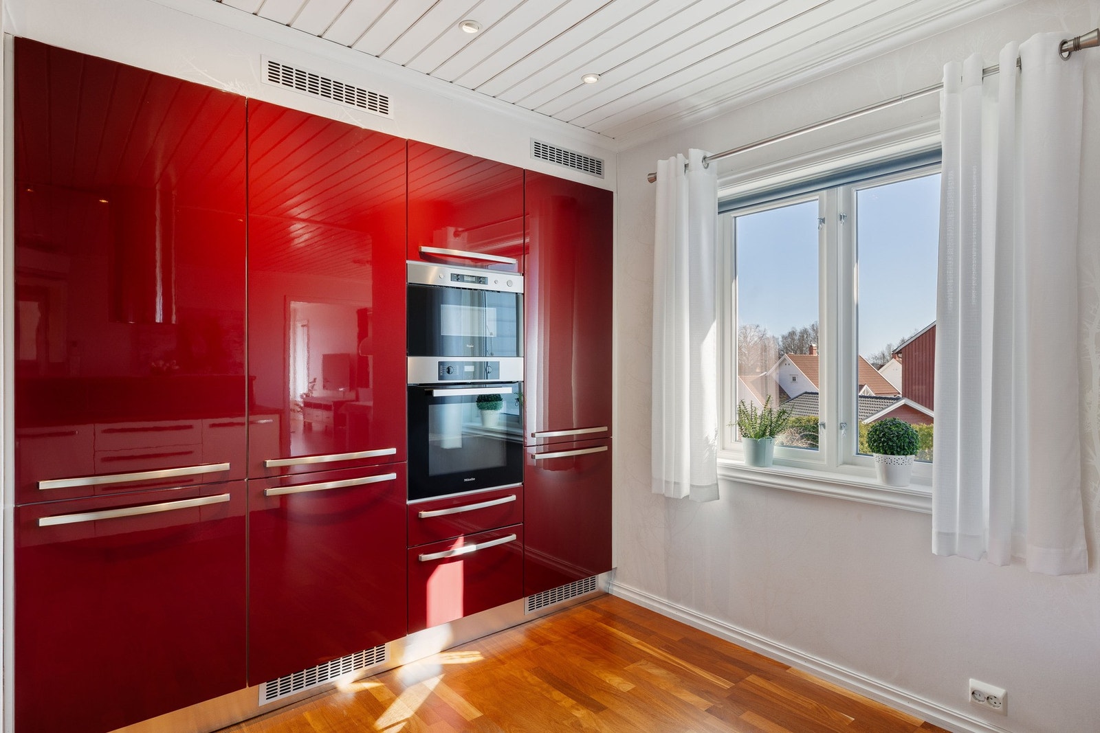 Moderne kjøkken med integrerte hvitevarer og detaljer som en rød kontrastvegg. Galleribilde