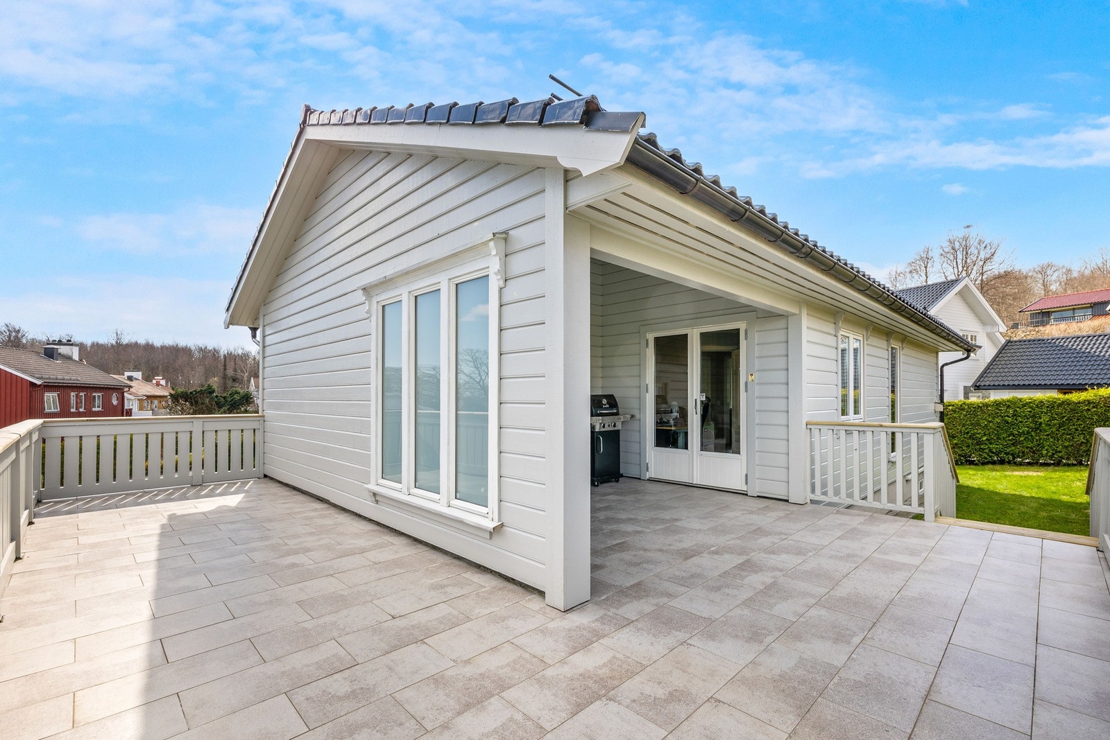 Lys og romslig terrasse med overbygd del og flislagt gulv. Galleribilde