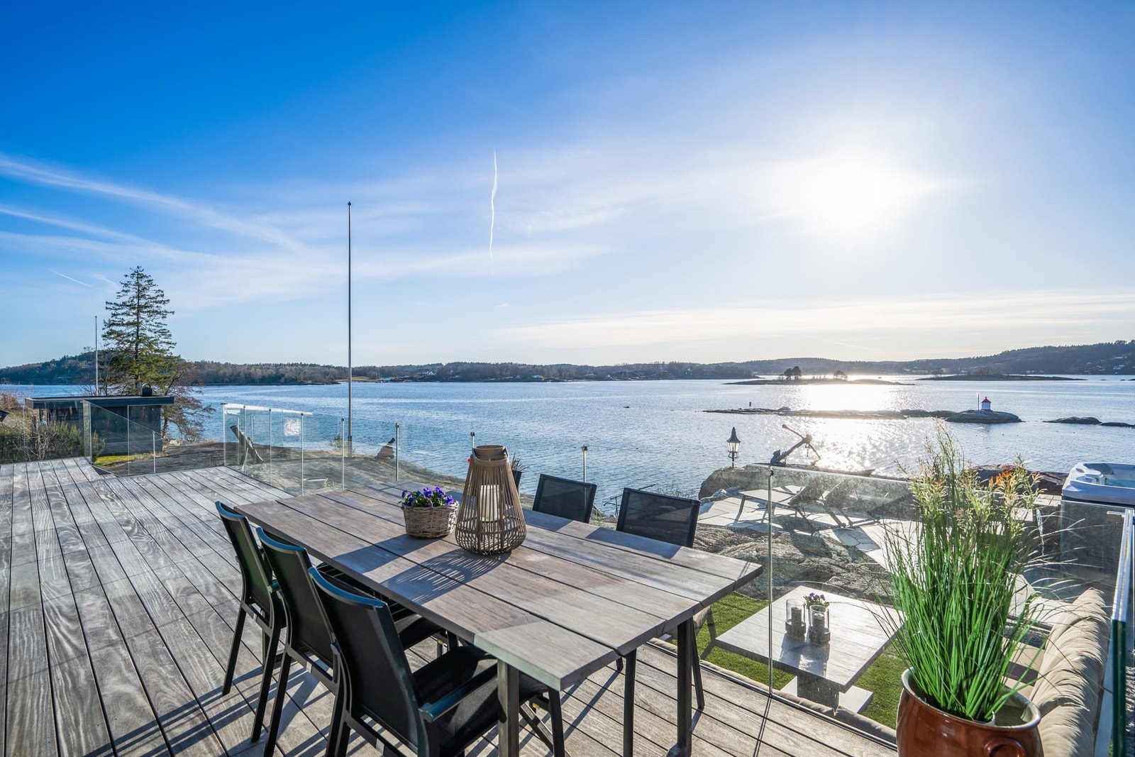 Utgang fra stue og spisestue i 1. etasje via store skyvedører til vestvendt terrasse oppført med vedlikeholdsvennlig tredekke og rekkverk i glass. Galleribilde