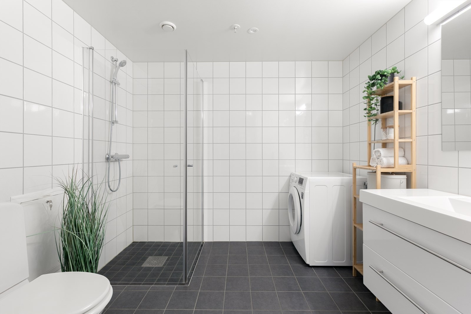 Badet har flislagte vegger og gulv med elektriske varmekabler, samt dusjhjørne med glassvegger. Galleribilde