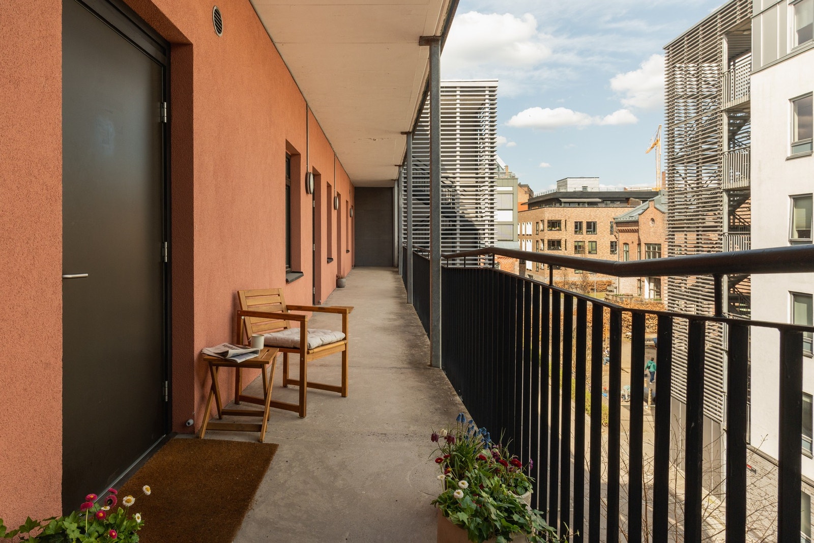 Adkomst til leiligheten via en bred og overbygget svalgang, med plass til en liten sittegruppe. Galleribilde
