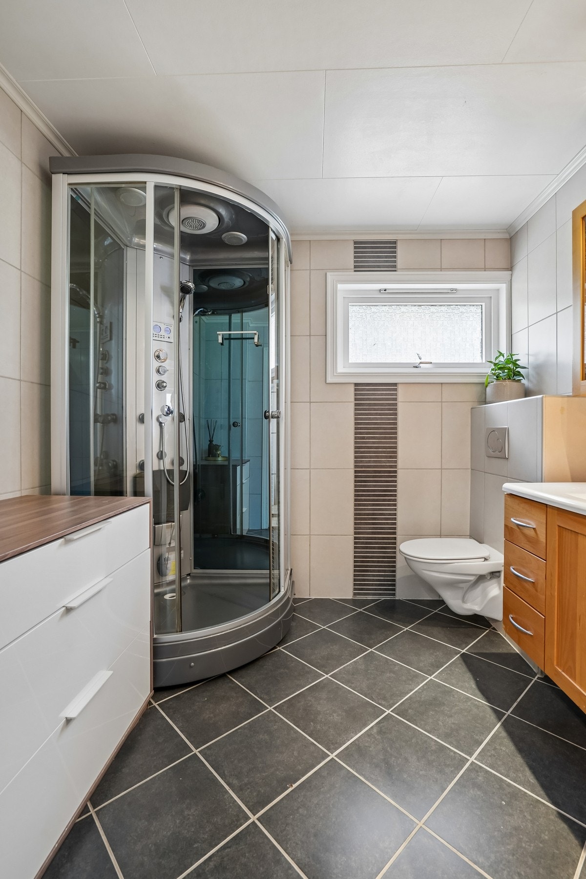 Badet er utstyrt med dusjkabinett og vegghengt toalett. Galleribilde