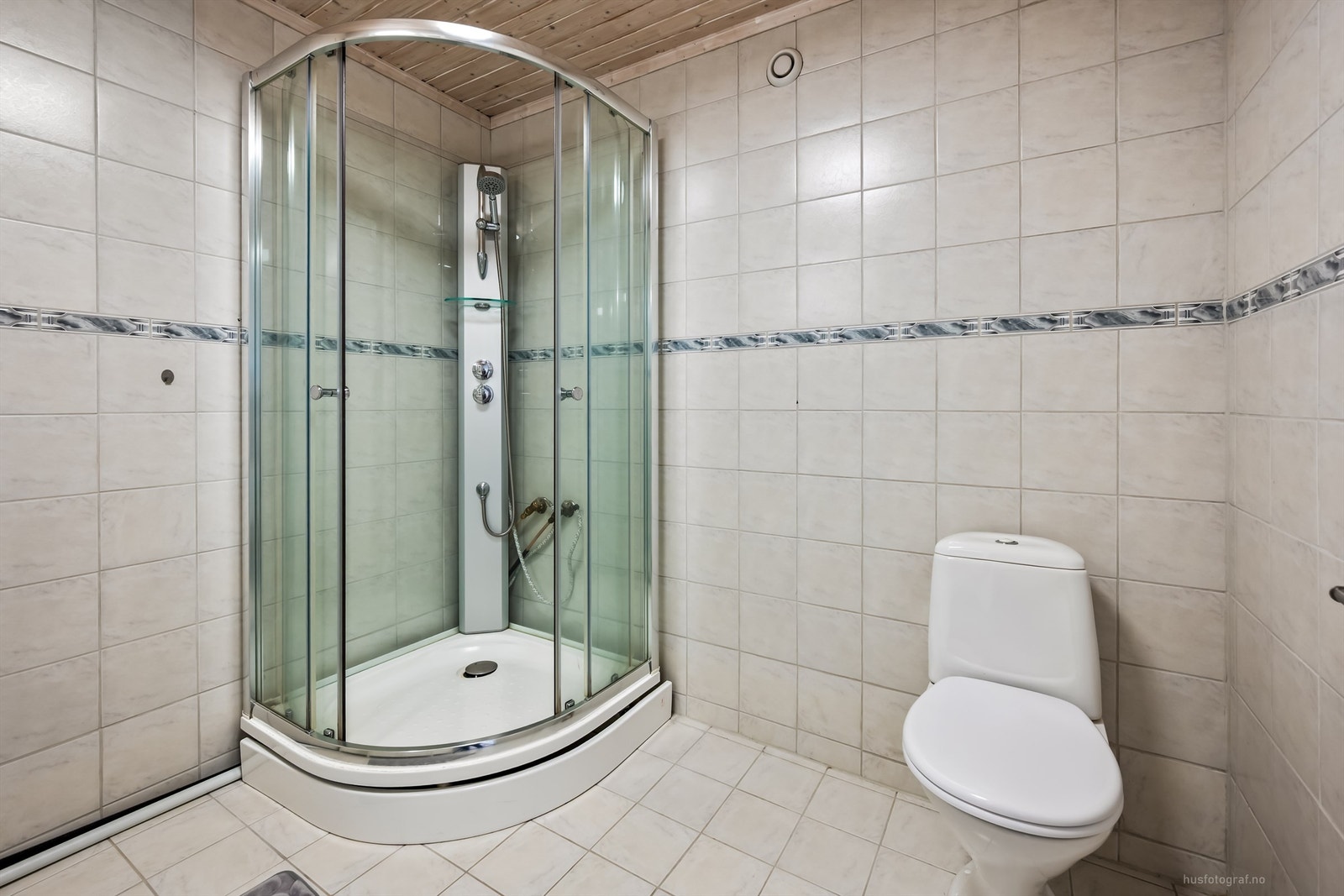 Badet er flislagt og har toalett og et romslig dusjkabinett. Galleribilde