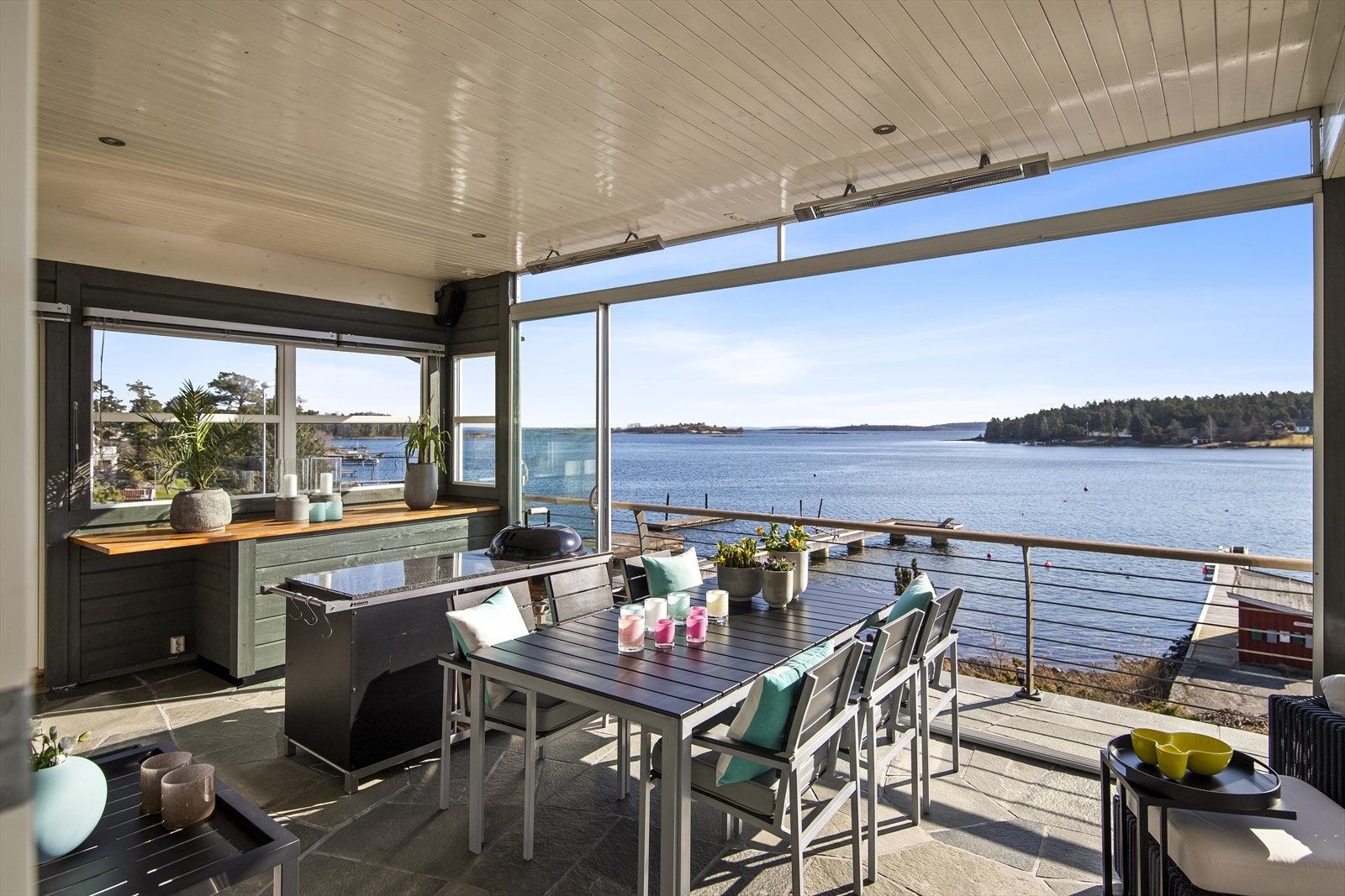 Deler av uteplassen består av en innglasset veranda, hvor vinduene kan skyves til side for å slippe solen og sommeren helt inn. Galleribilde