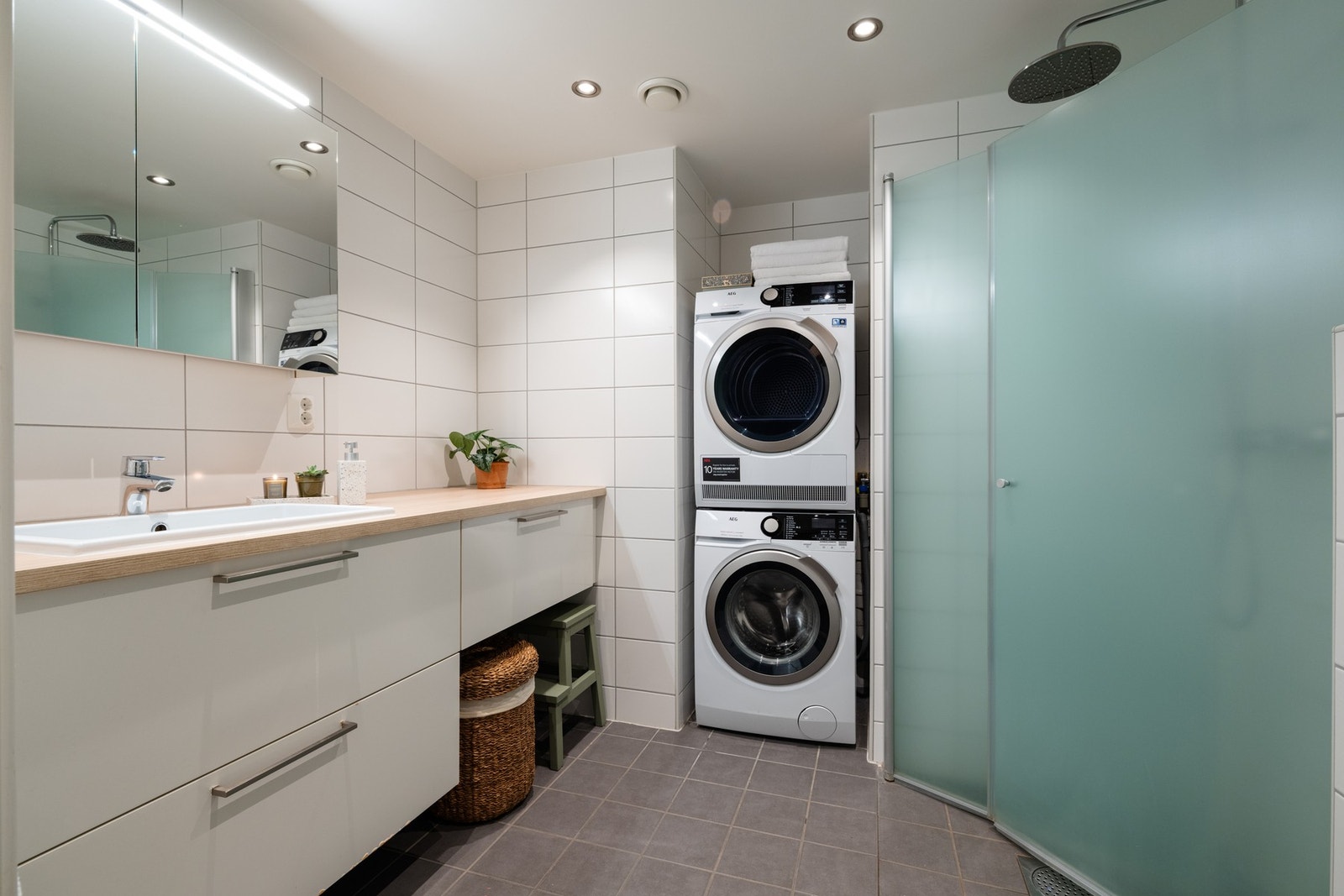Boligens bad er lyst flislagt med varme i gulv og downlights i himling. Badet har opplegg for vaskemaskin og plass til tørketrommel i praktisk nisje. Galleribilde