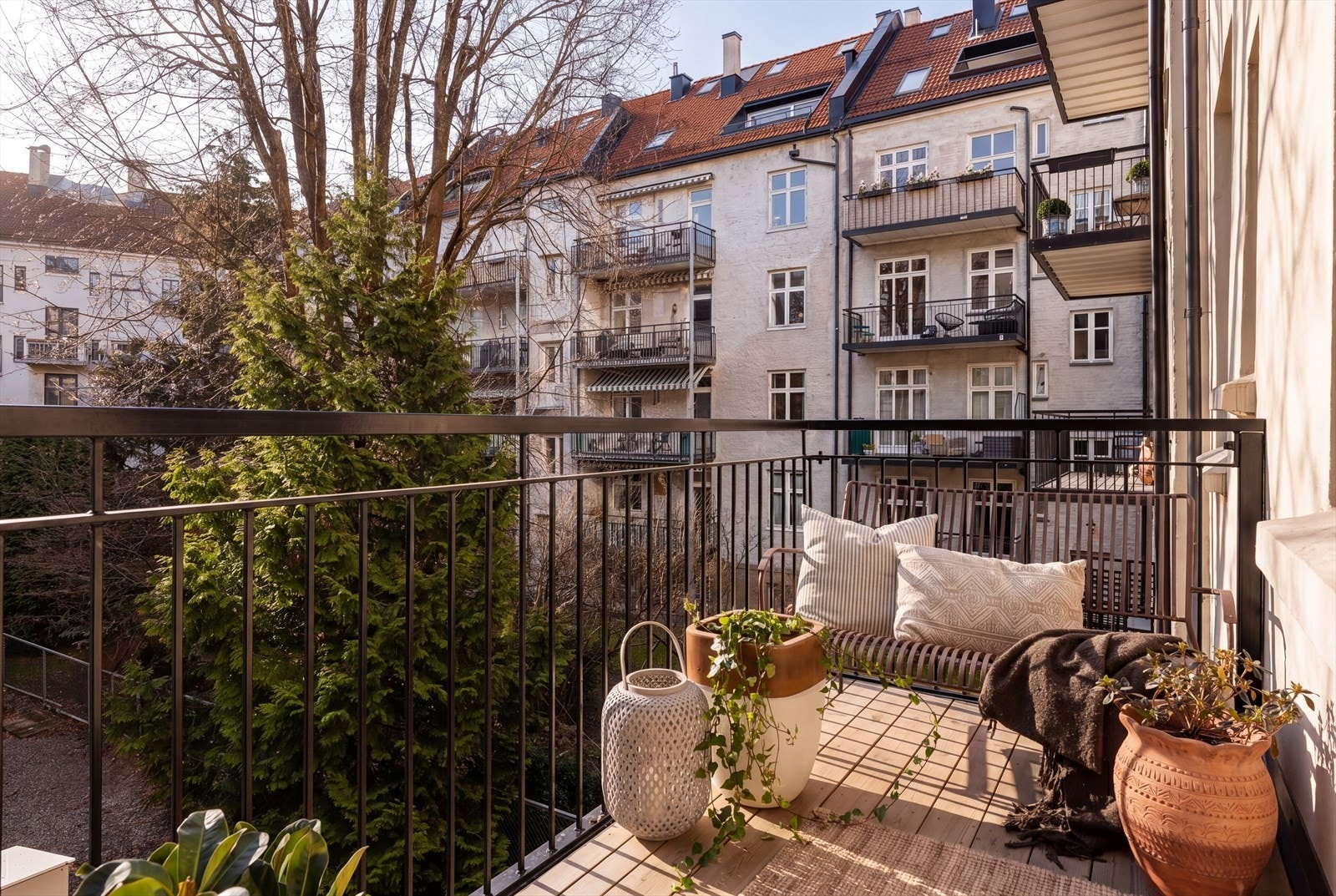 Leiligheten har til og med en stor og herlig balkong som vender mot indre gårdsrom og har ettermiddagssol om sommeren. Bildet er AI-redigert med sol-effekt da bildet ble tatt tidlig på dagen, avvik kan derfor forekomme. Galleribilde