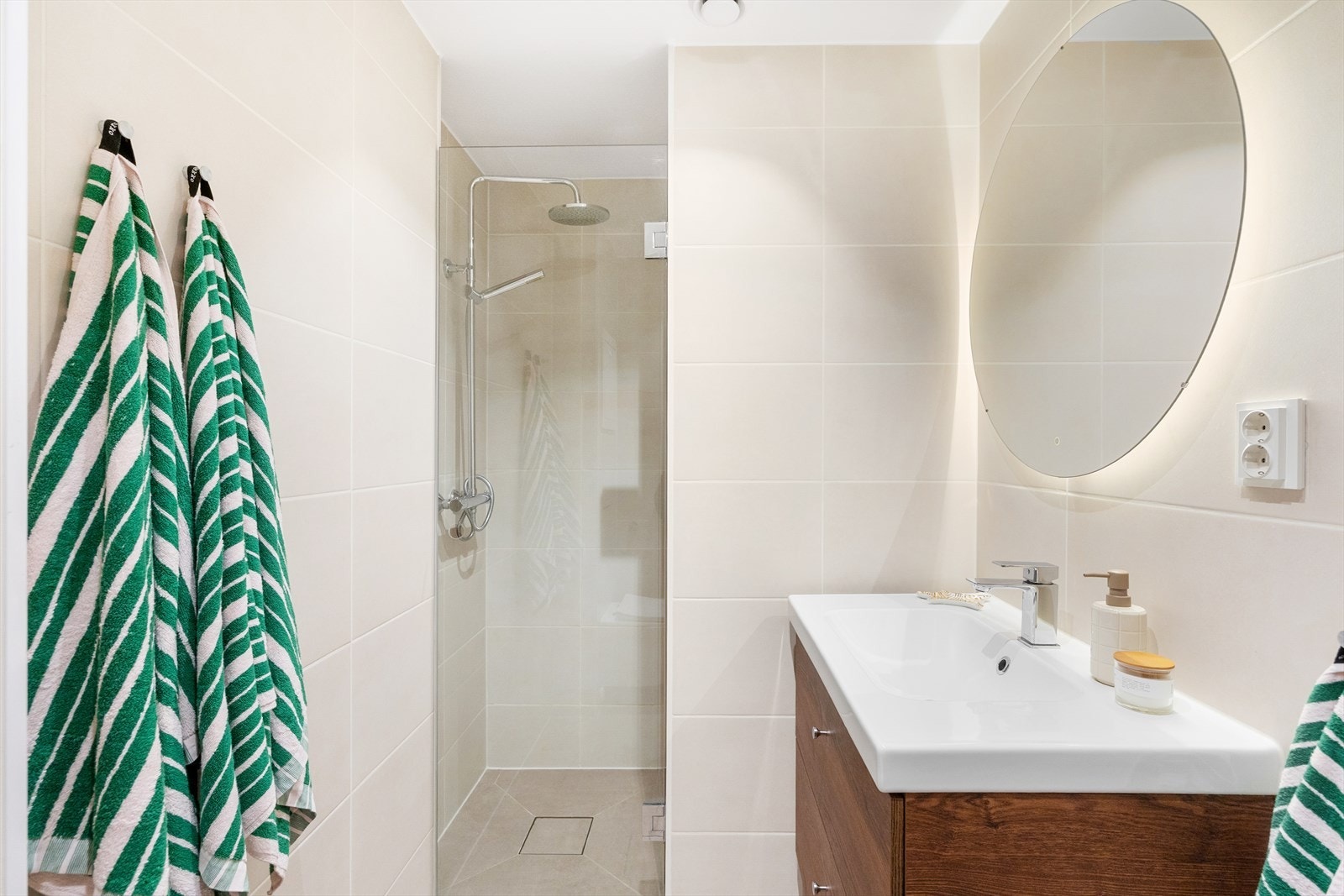 Badet er utstyrt med servantskap med folierte fronter og heldekkende servant, speil med belysning, veggmontert toalett og dusjhjørne med regnfallsdusj. Galleribilde