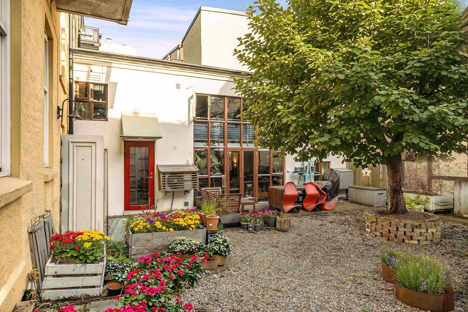 Hyggelig bakgård med plass til sittegrupper. Blomster er Ai generert. Galleribilde