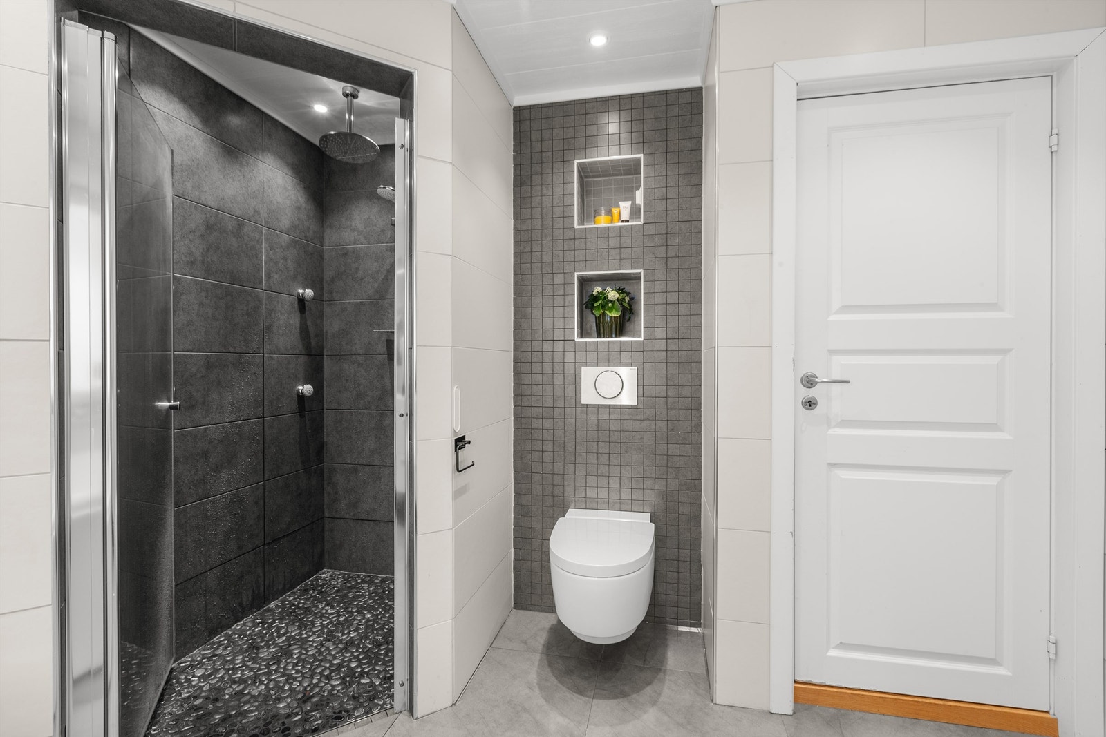 Badet er utstyrt med dobbeltservant, vegghengt toalett og praktiske nisjehyller for oppbevaring. Galleribilde