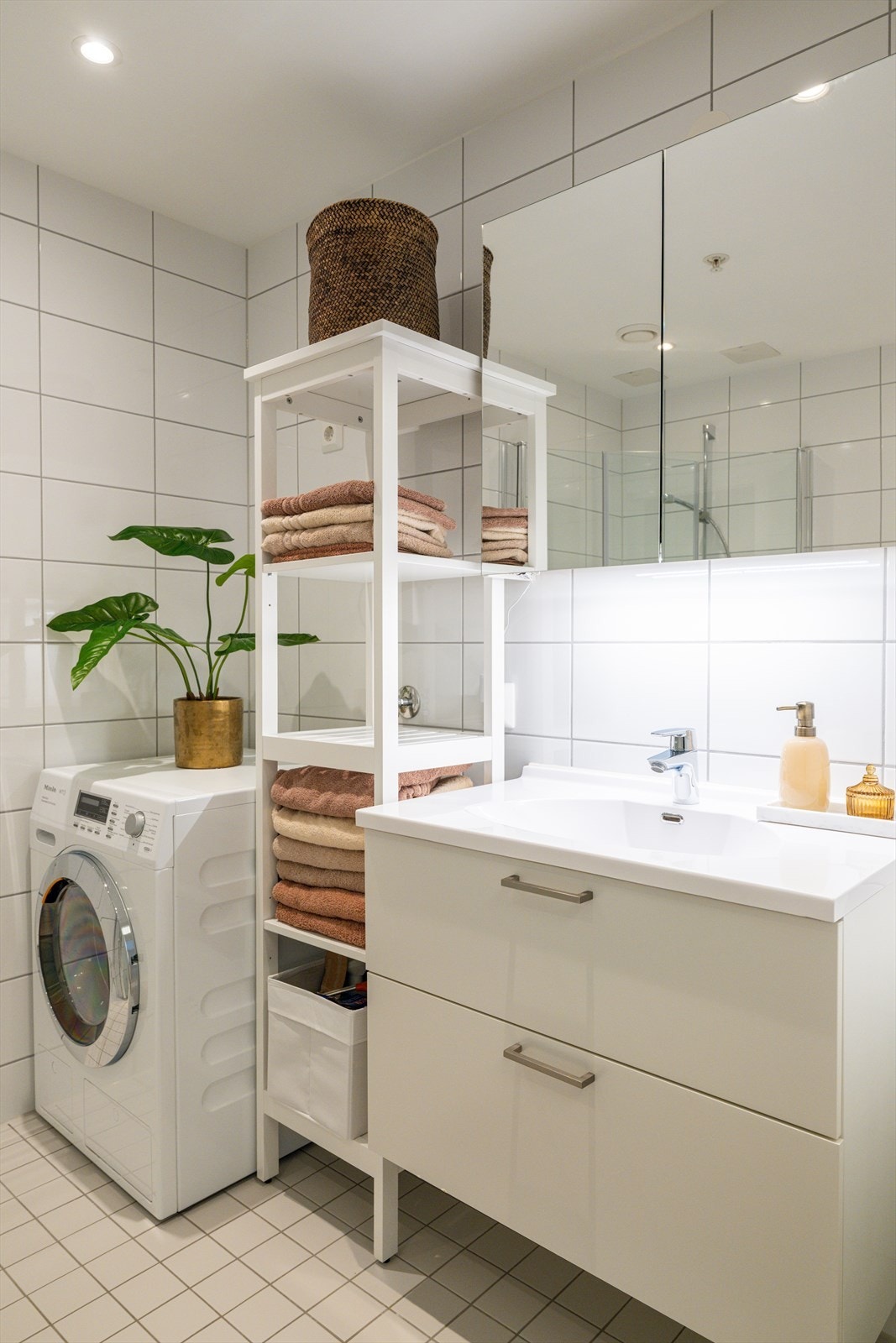Badet er innredet med servantskap med nedfelt servant, veggskap med speildører samt vegghengt klosett. Dusjsonen har innfelte dusjdører i glass, og det er i tillegg opplegg for vaskemaskin Galleribilde