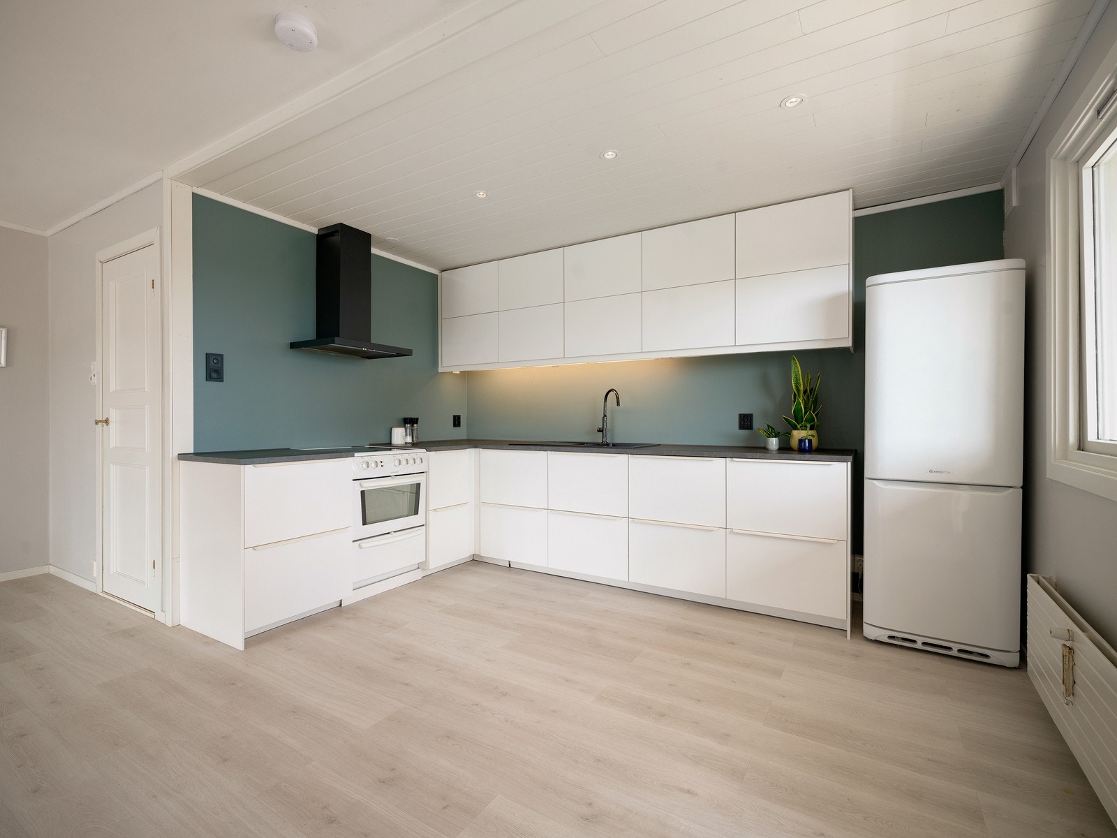 Kjøkkenet har en moderne og lekker innredning med hvite, glatte fronter og en laminert benkeplate med nedfelt kjøkkenkum. Galleribilde