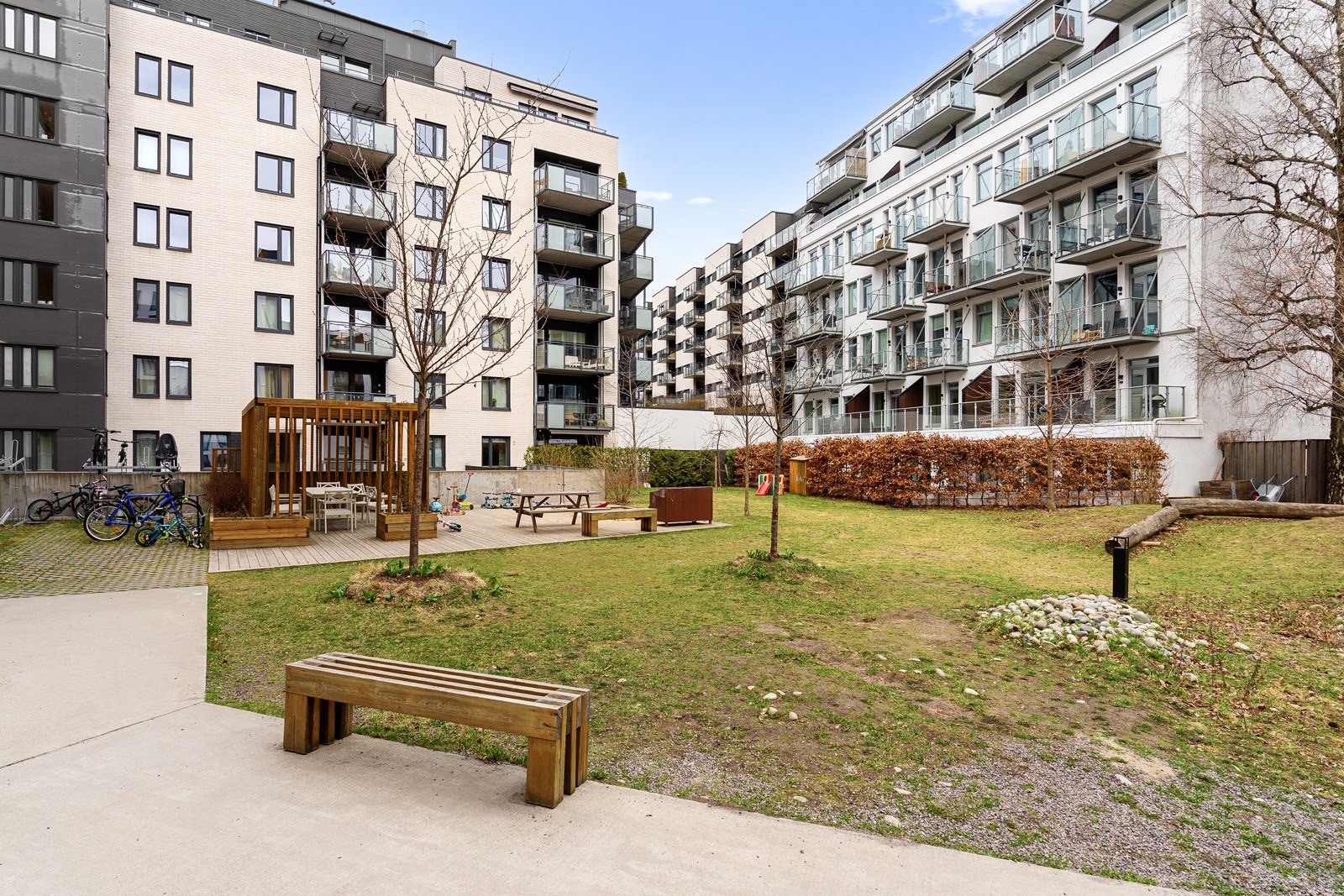 Stort fellesareal, pent opparbeidet med betonglagt adkomstvei, gressplen, beplantning, sittegrupper, lekeplass m.m. Galleribilde
