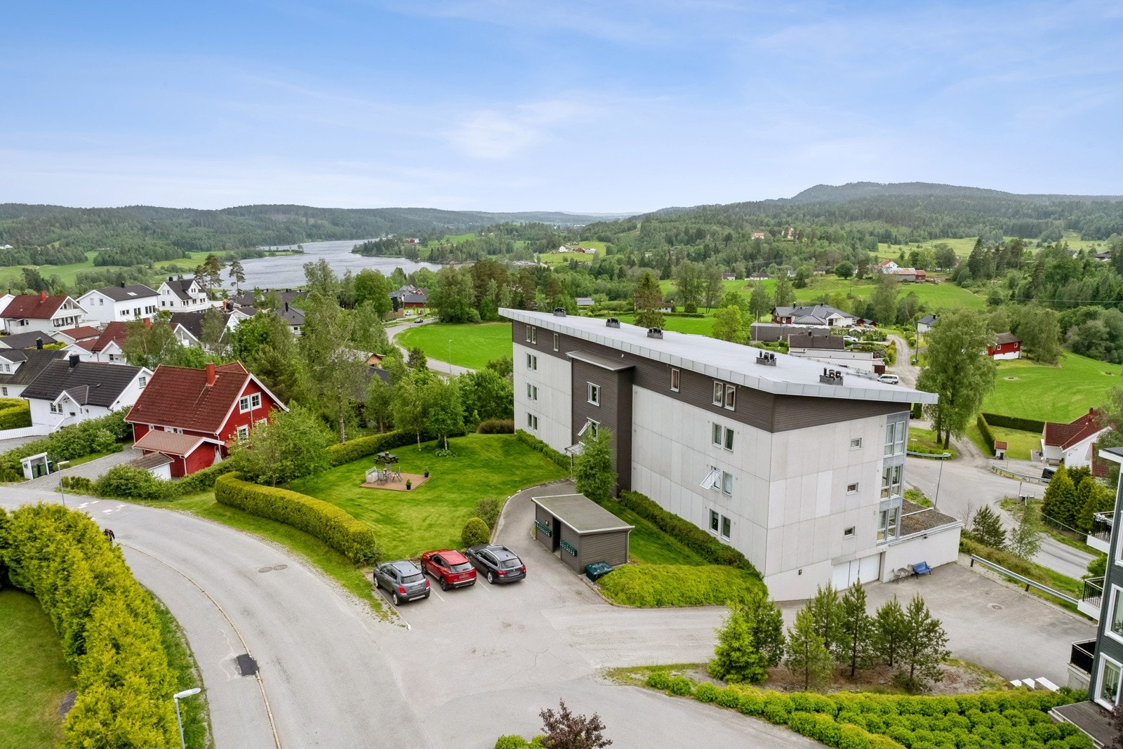 Det er velpleide fellesarealer rundt bygningen, og flere gjesteparkeringsplasser (dronefoto) Galleribilde