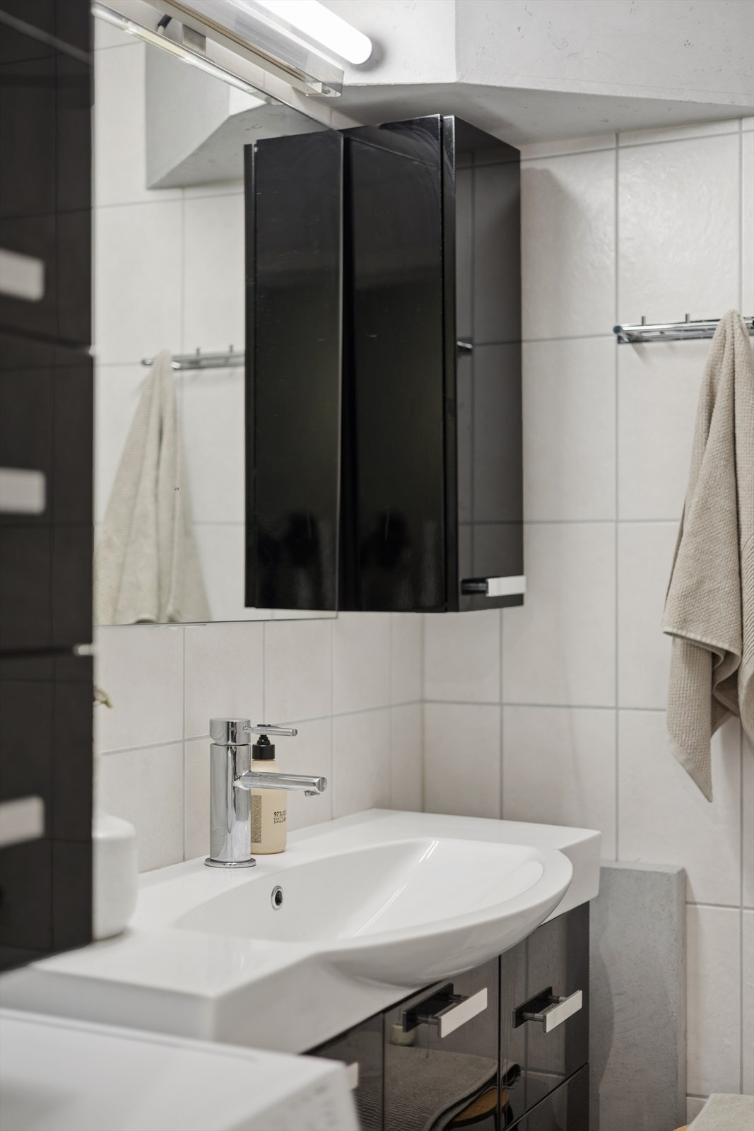 Badet har innredning med glatte fronter og heldekkende servant, med speil og belysning på veggen over. Galleribilde