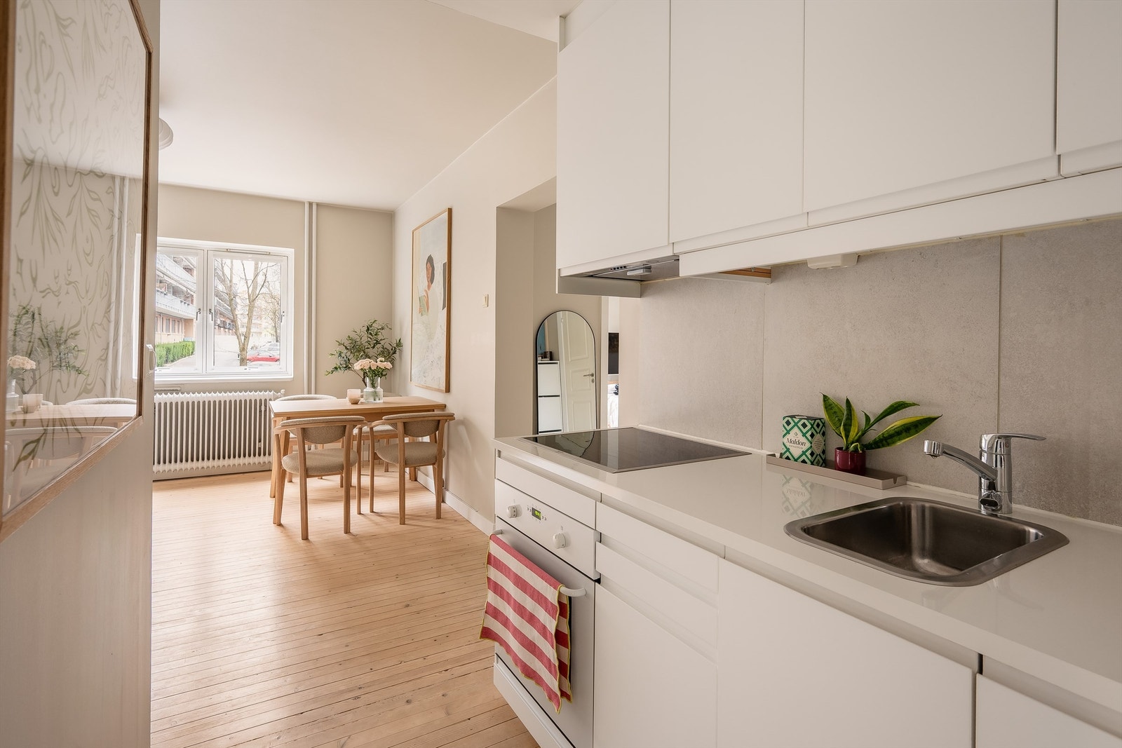 Innredningen med integrerte hvitevarer, lyse fronter, laminat benkeplate med nedfelt kum i rustfritt stål Galleribilde