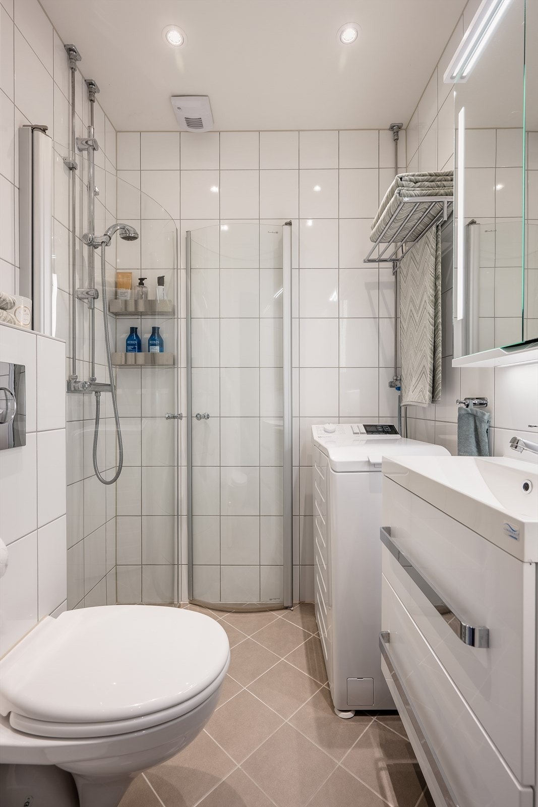 Flislagt baderom, tatt i regi av borettslaget i 2015, med varmekabler, downlights og opplegg for vaskemaskin Galleribilde