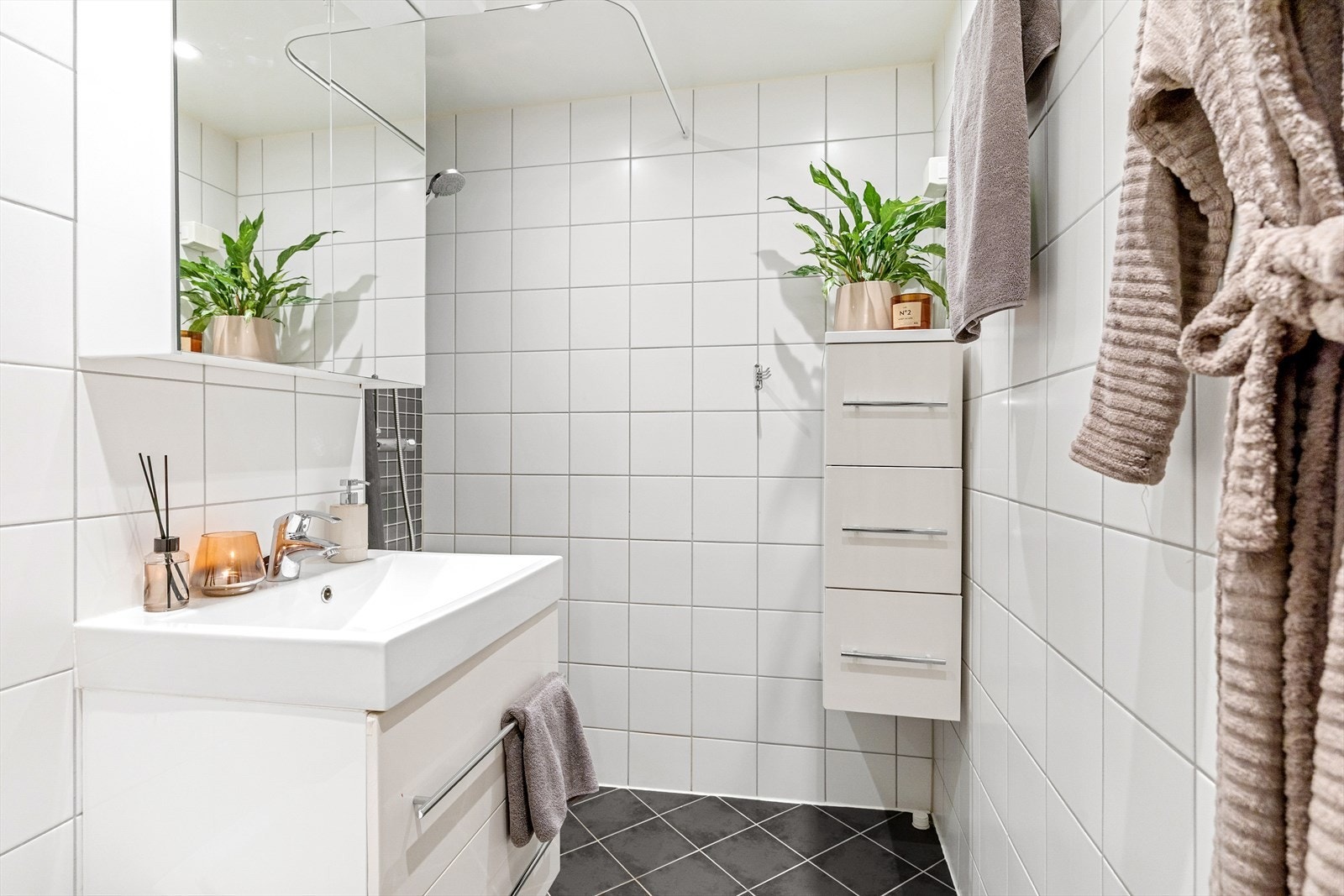 Baderommet er innredet med vegghengt klosett, dusjhjørne, speilskap med belysning, veggmontert innredning, og innredning med servant. Det er opplegg for vaskemaskin. Galleribilde