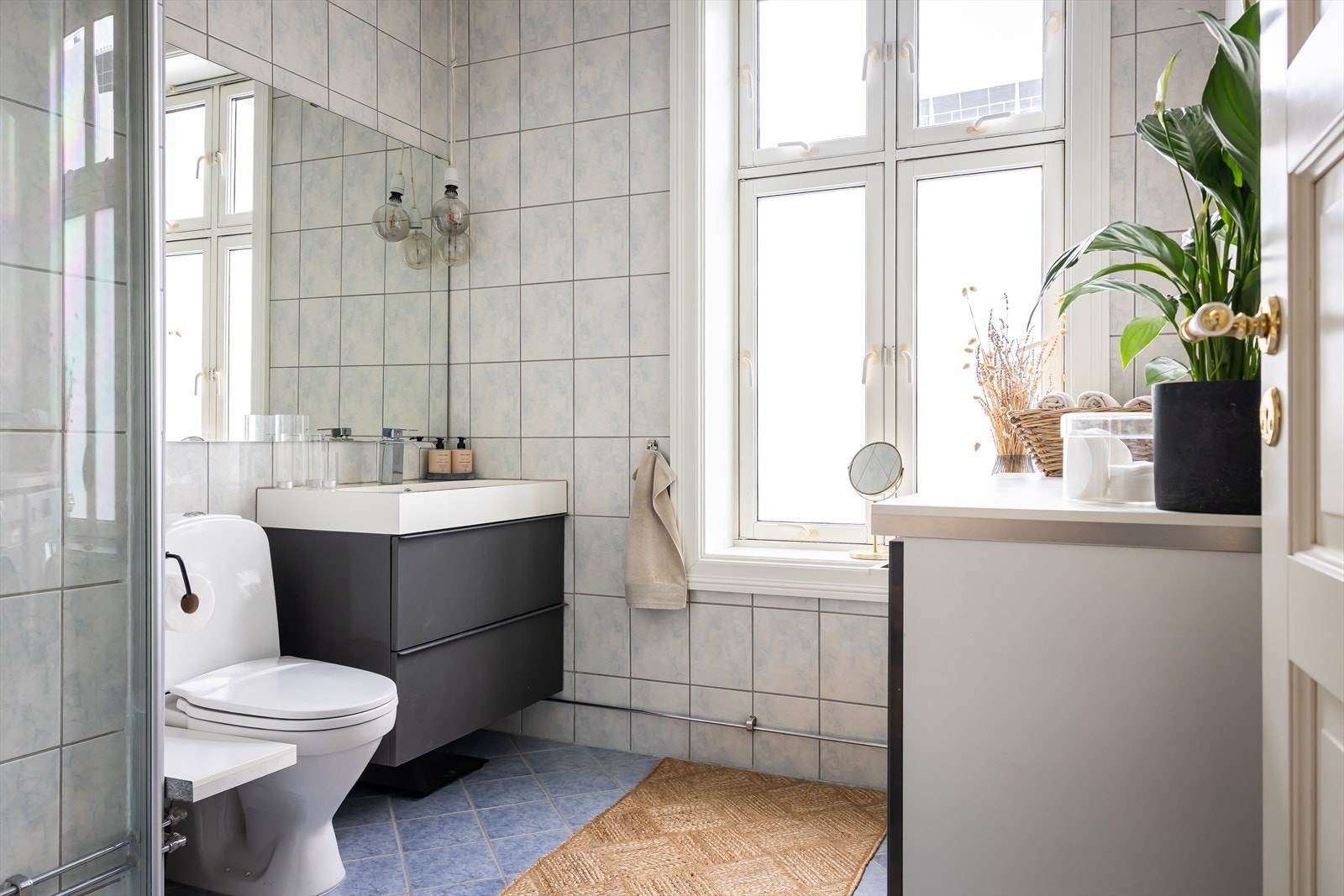 Romslig flislagt bad med gulvvarme og vindu som slipper inn naturlig lys. Badet er utstyrt med dusjhjørne, servantskap og gulvmontert toalett. Galleribilde