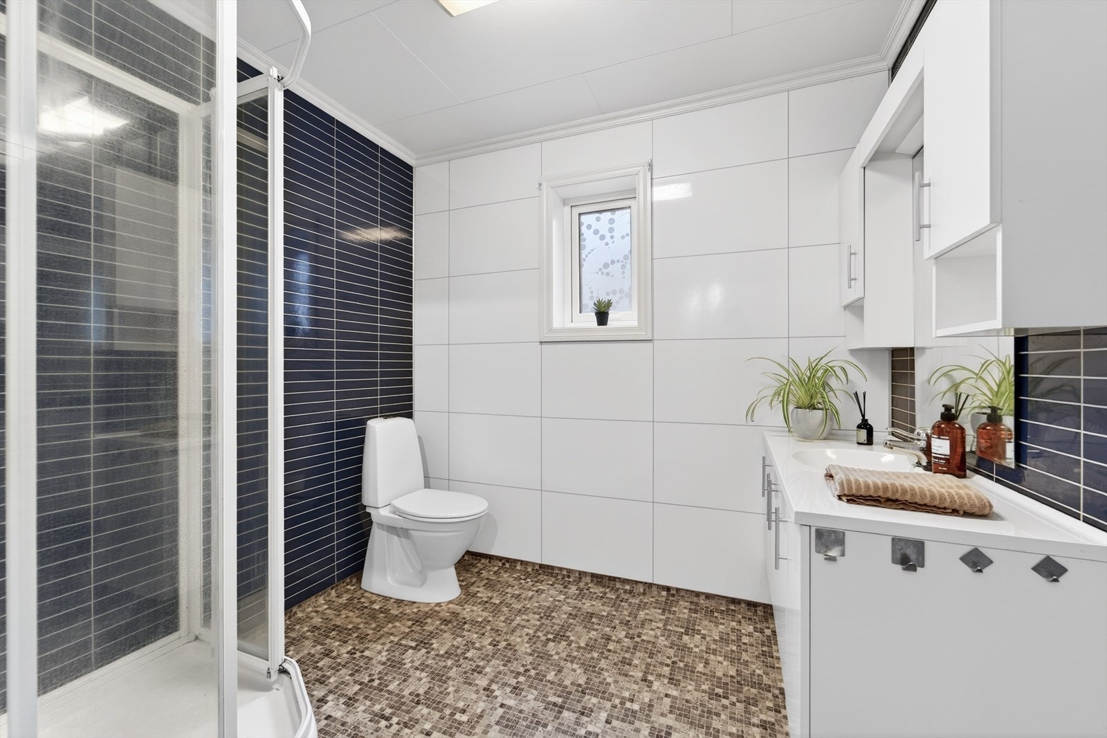 Baderom med lys og moderne innredning. På veggene er det baderomsplater og på gulv er det belegg med varmekabler. Galleribilde