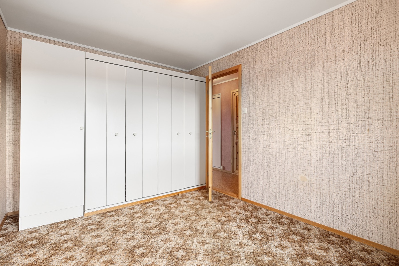 Teppe på gulv og tapet på vegger. Malt overflate i himling. Panelovn. Garderobeskap. Galleribilde
