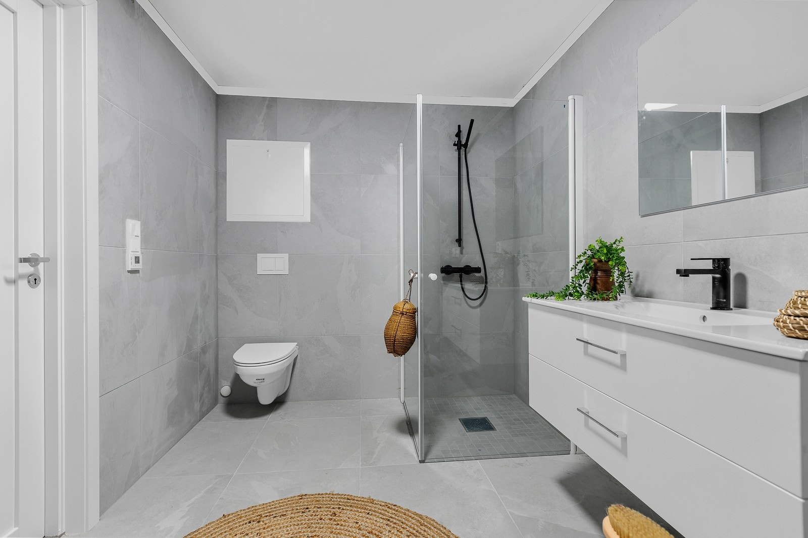 Badet har moderne baderomsinnredning og har innredning med speil, dusjhjørne, vegghengt toalett og opplegg for vaskemaskin. Galleribilde