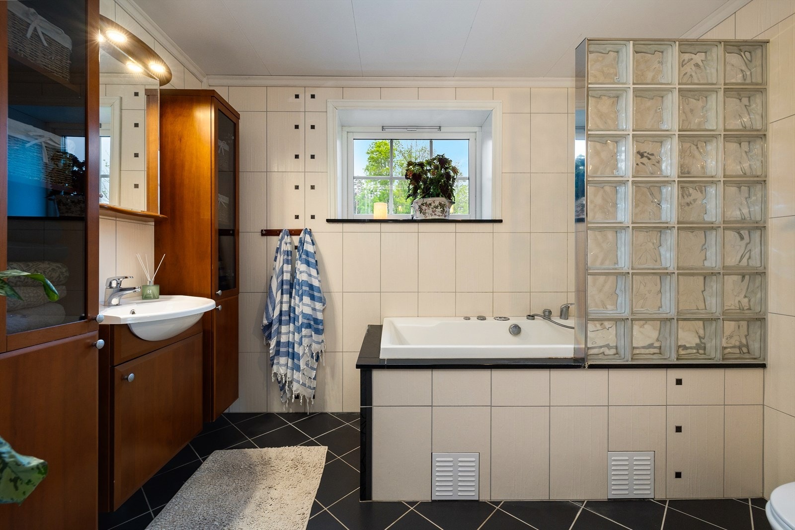 Badet ligger i tilknytning til kjøkkenet og er pent innredet med fliser, vegghengt toalett, boblekar med dusj og god skapplass. Galleribilde