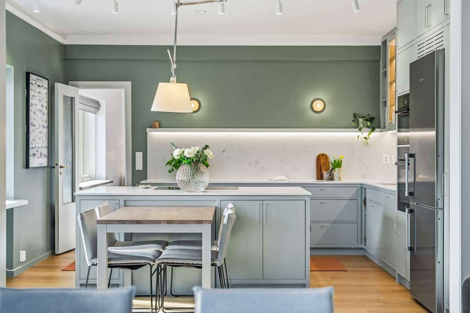 Stor kjøkkenøy med platetopp og integrert kullfiltervifte fra Miele. Det er integrerte stikkontakter på begge sider av kjøkkenøyen. Galleribilde