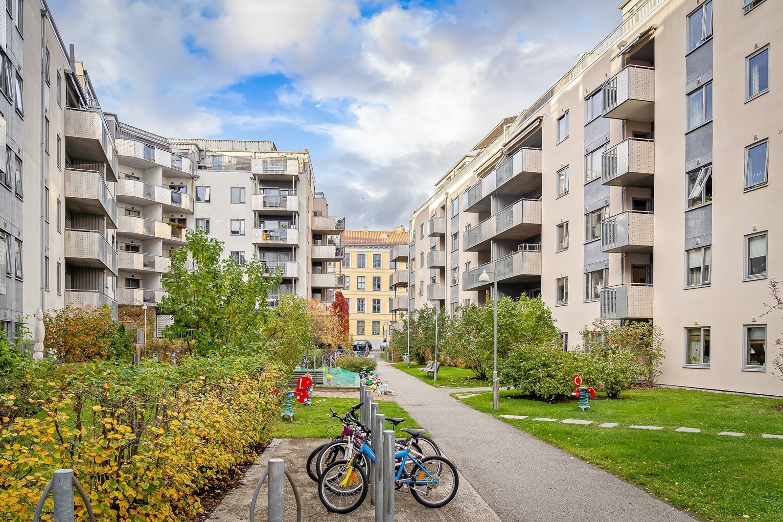 Pent opparbeidet bakgård med gressplen, beplantning og felles sykkelparkering Galleribilde