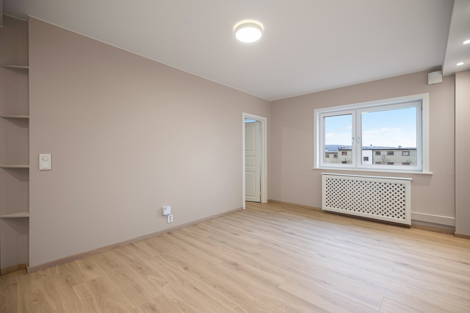Lys og luftig stue med parkett og god romfølelse. Hyller på veggen til venstre gir praktisk oppbevaringsplass. Galleribilde
