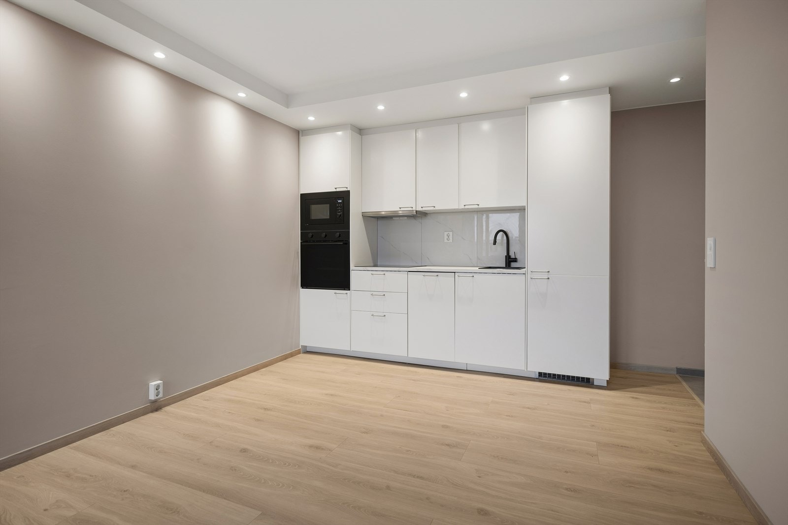 Kjøkkenet sett fra motsatt side av stuen. God plass til spisebord i tilknytning til kjøkkenet. Galleribilde