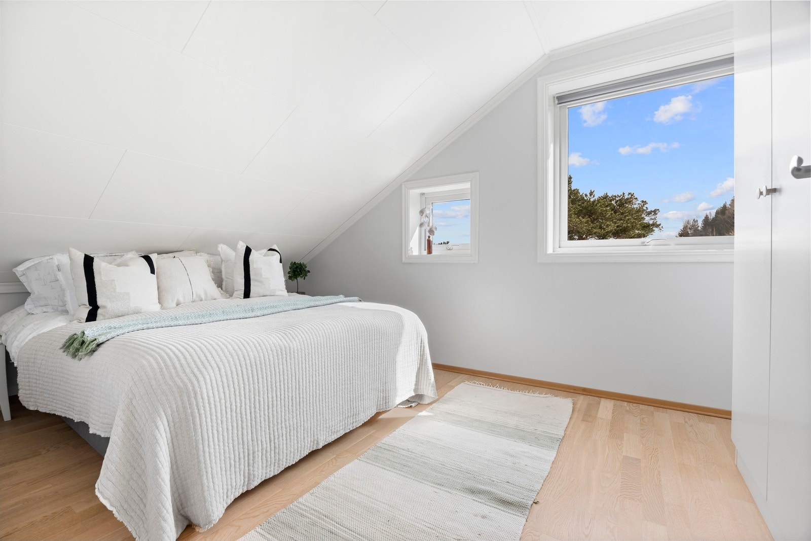 Lyst soverom med skråtak og store vinduer som gir godt med naturlig lys. Galleribilde