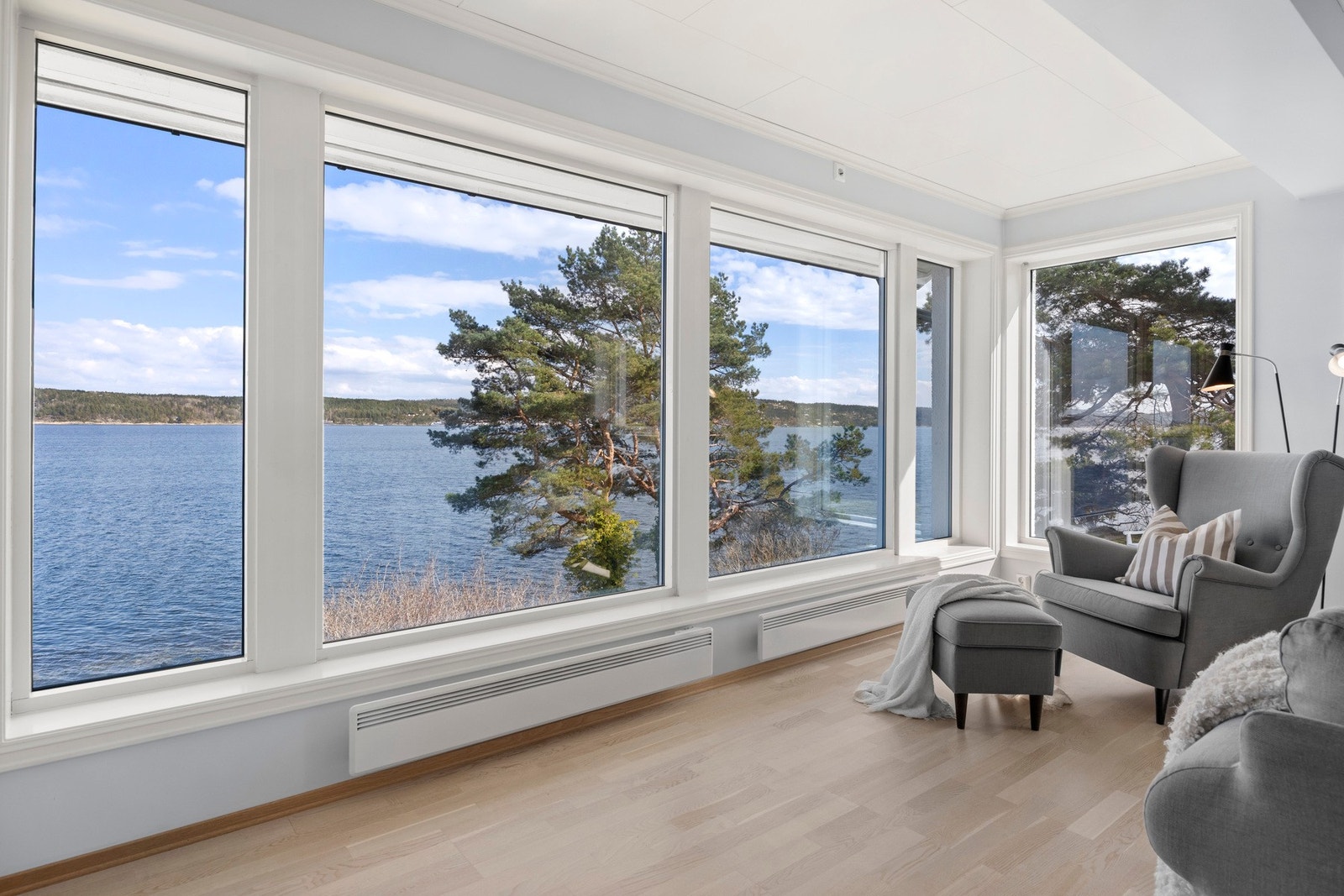 Store vinduer med utsikt over vannet og trær gir en lys og luftig følelse. Galleribilde