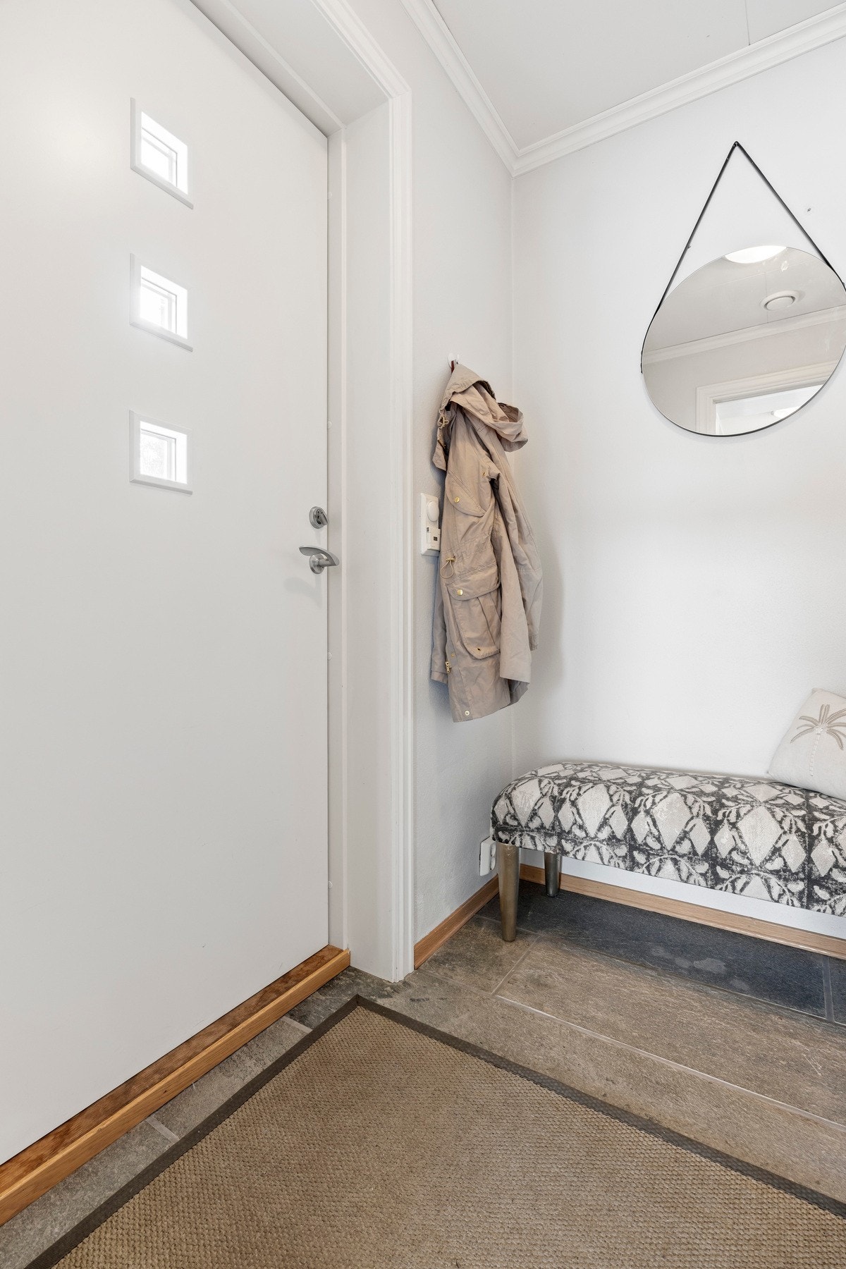 Lys gang med fliser på gulvet og hvit dør med små vinduer. Galleribilde